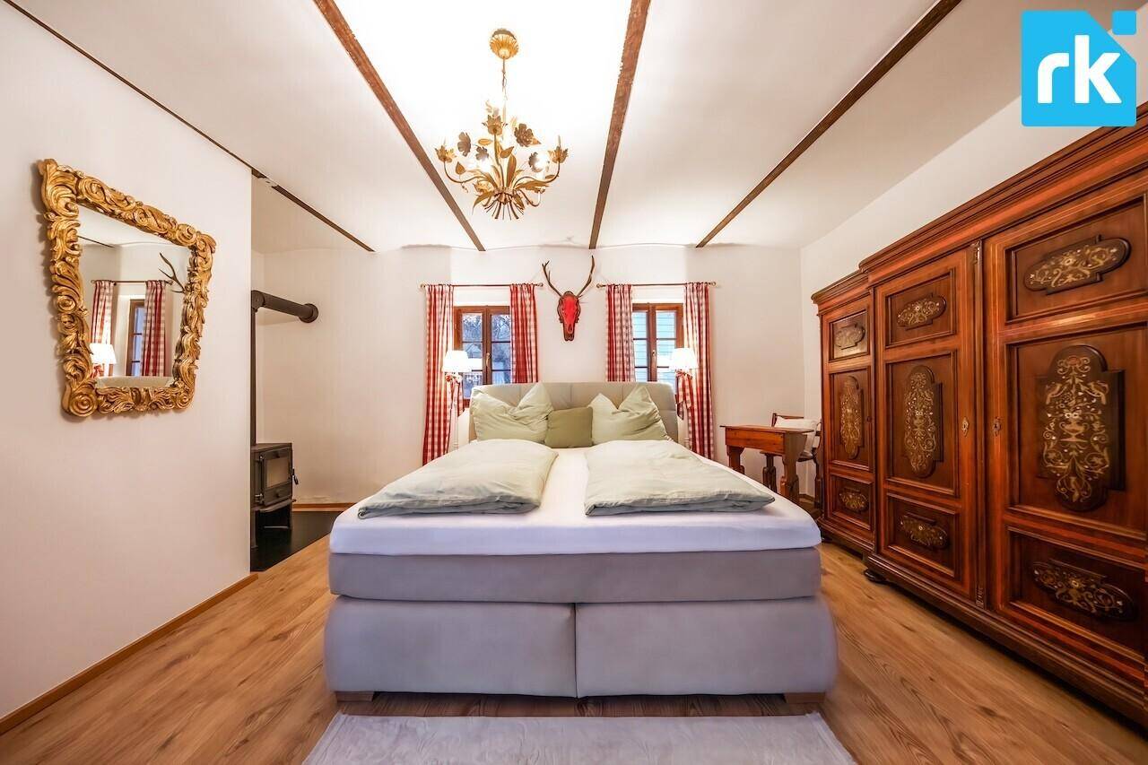 Gemütliches Schlafzimmer mit Holzbalken an der Decke, großem Bett und traditionellem Kleiderschrank.