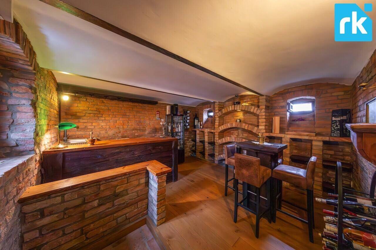 Rustikaler Weinkeller mit unverputzten Ziegelwänden, Holztheke und Weinregalen.