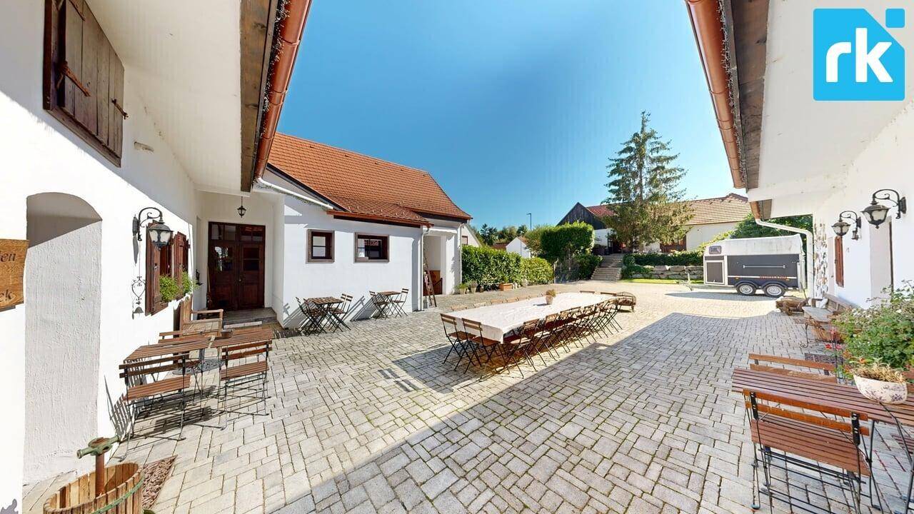 Sonniger Innenhof mit gepflastertem Boden und mehreren Sitzgelegenheiten für gesellige Stunden.