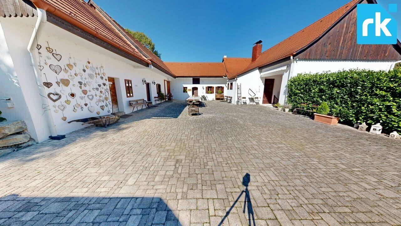 Großer gepflasterter Innenhof, umgeben von traditionellen Gebäuden mit roten Dächern, sehr charmant.