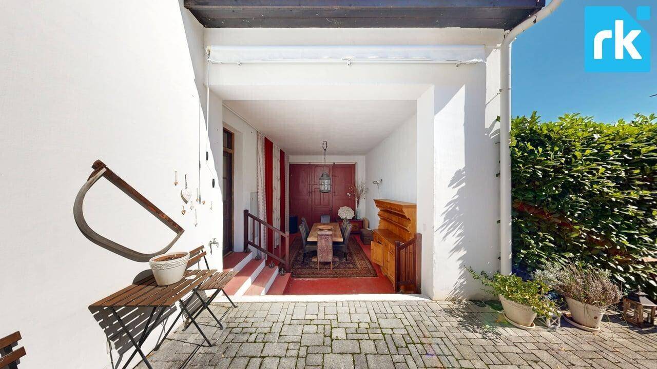 Überdachter Eingangsbereich mit kleiner Sitzecke, der in einen gemütlichen Innenraum führt.