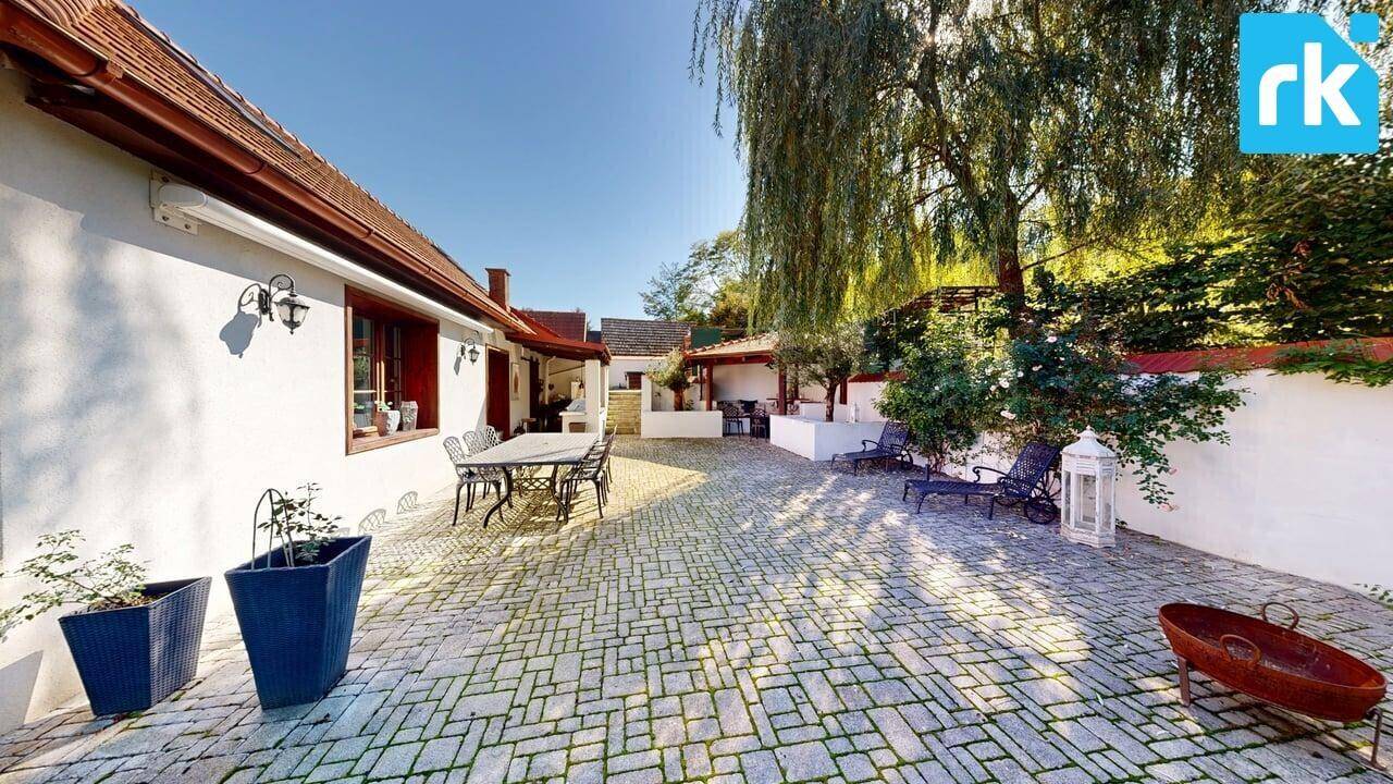 Großer gepflasterter Innenhof mit Sitzgelegenheiten und Bäumen, ideal für entspannte Stunden im Freien.