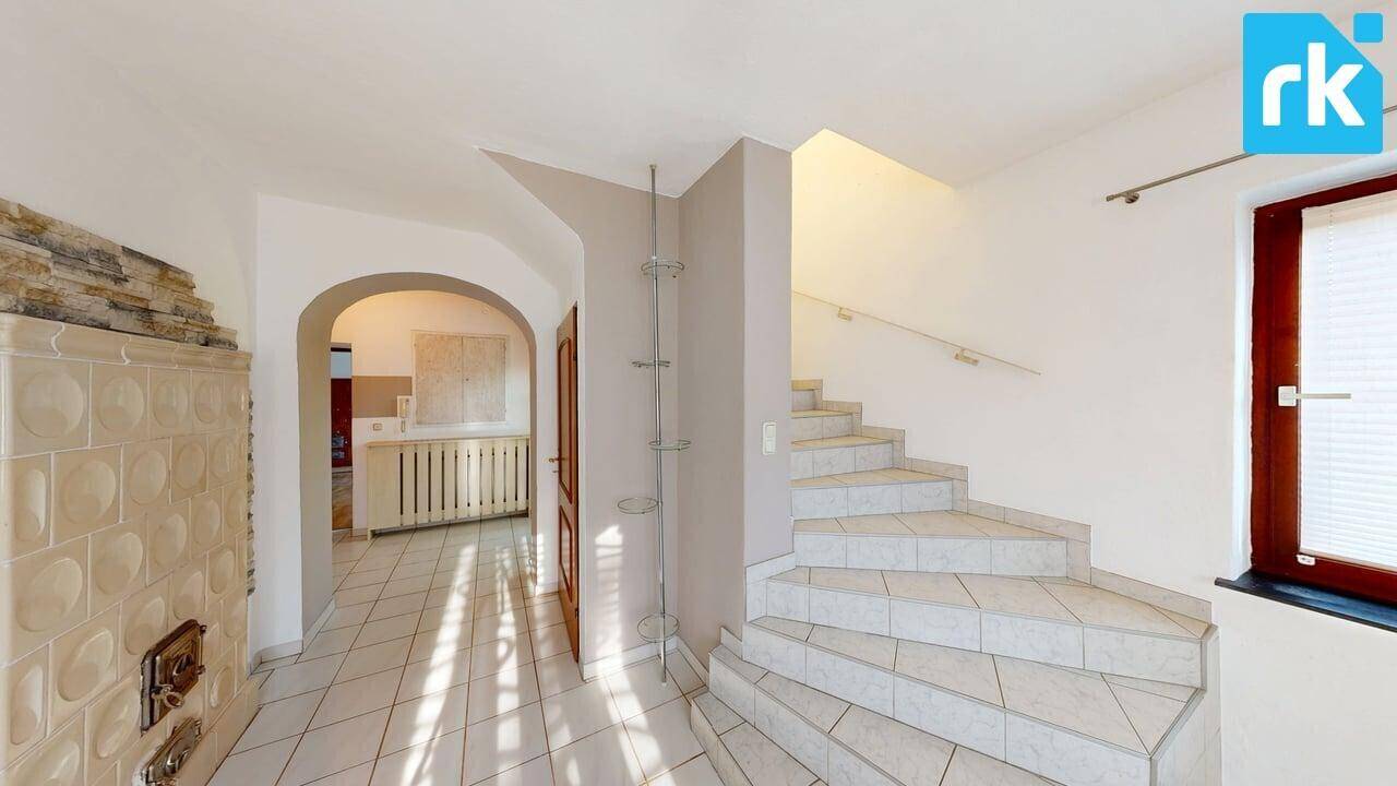 Geräumiger Flur mit gefliester Treppe und Kachelofen, der zu den oberen Etagen führt.