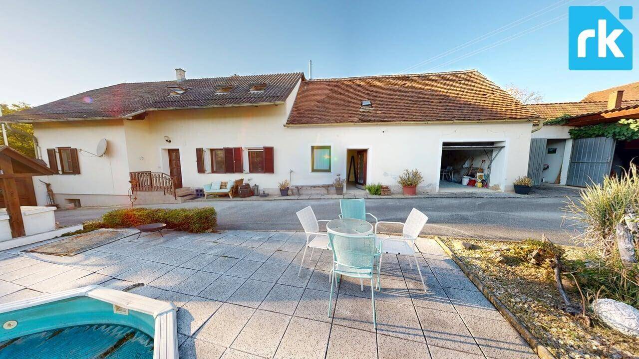 Sonniger Außenbereich mit gepflasterter Terrasse, Gartenmöbeln und Blick auf den Pool.