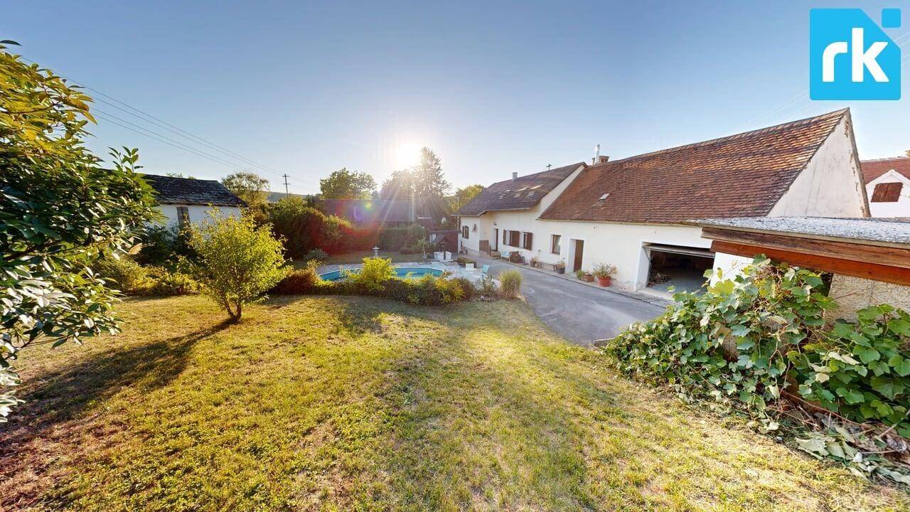 Großer, gepflegter Garten mit Rasenfläche und Blick auf das Haus mit Pool.