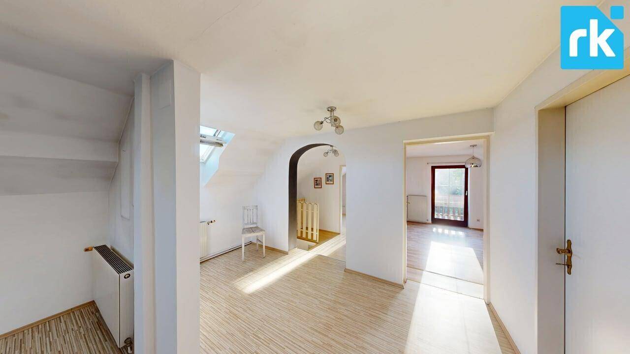 Heller Flur im Obergeschoss mit Holzboden, Dachfenster und Zugang zu weiteren Räumen.