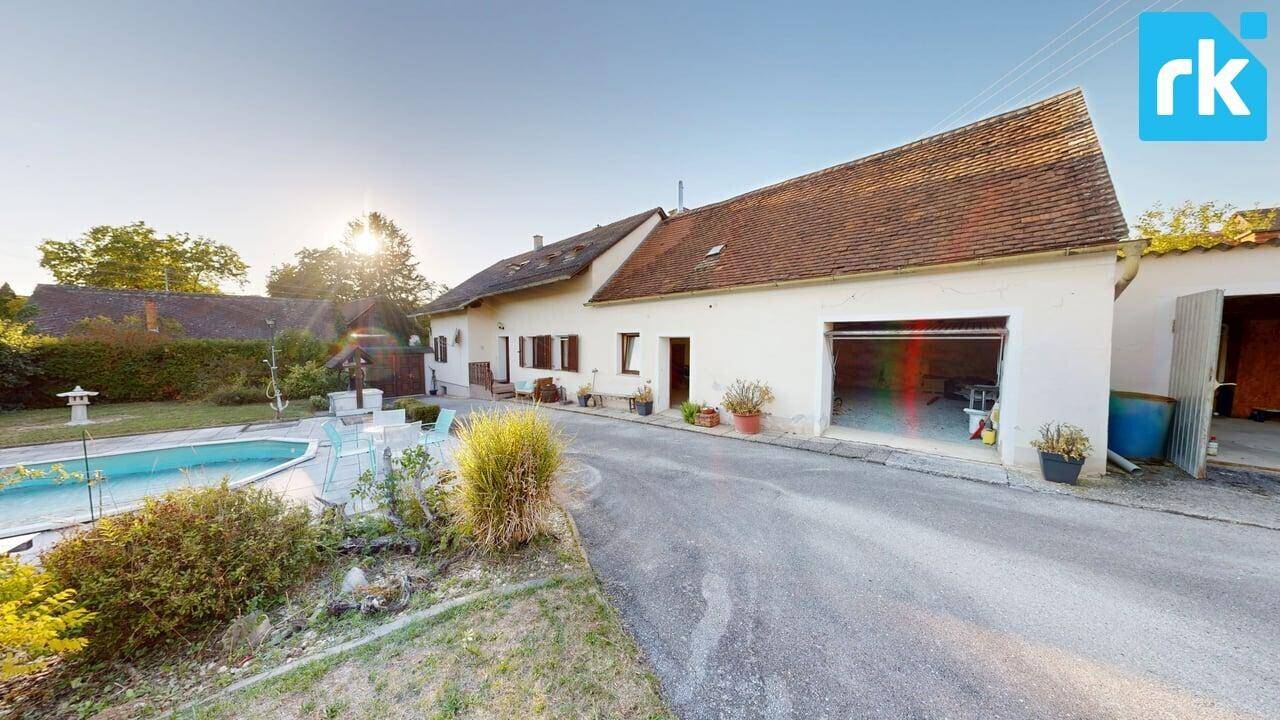 Weitläufiger Gartenbereich mit Swimmingpool und dem Haupthaus unter blauem Himmel.