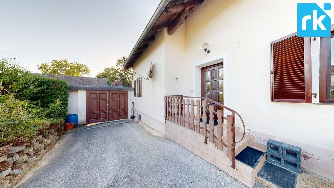 Seitlicher Eingangsbereich des Hauses mit Treppe, Fensterläden und Zufahrt.