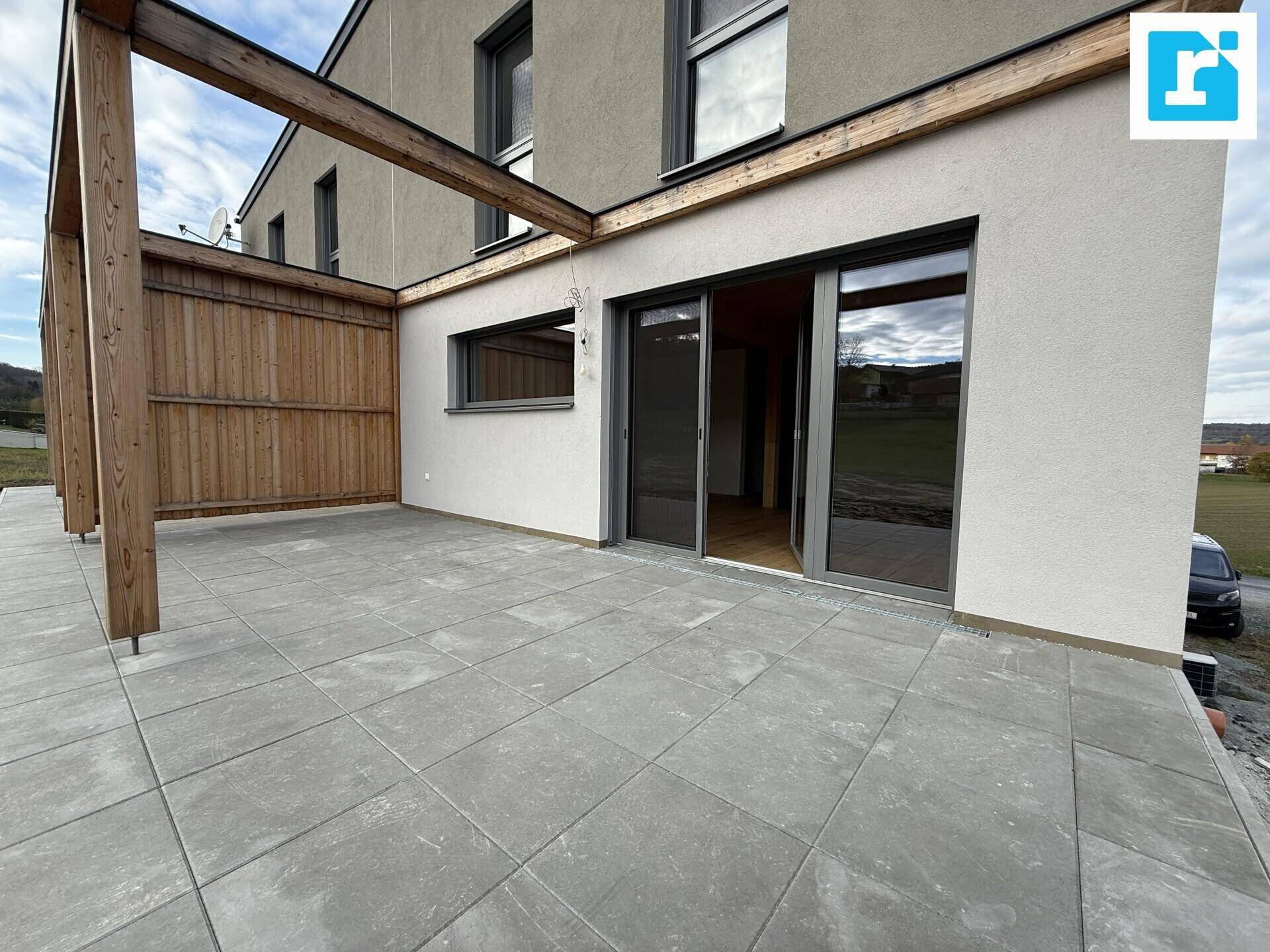 Große, geflieste Terrasse mit Holzpergola und Zugang zum Haus.