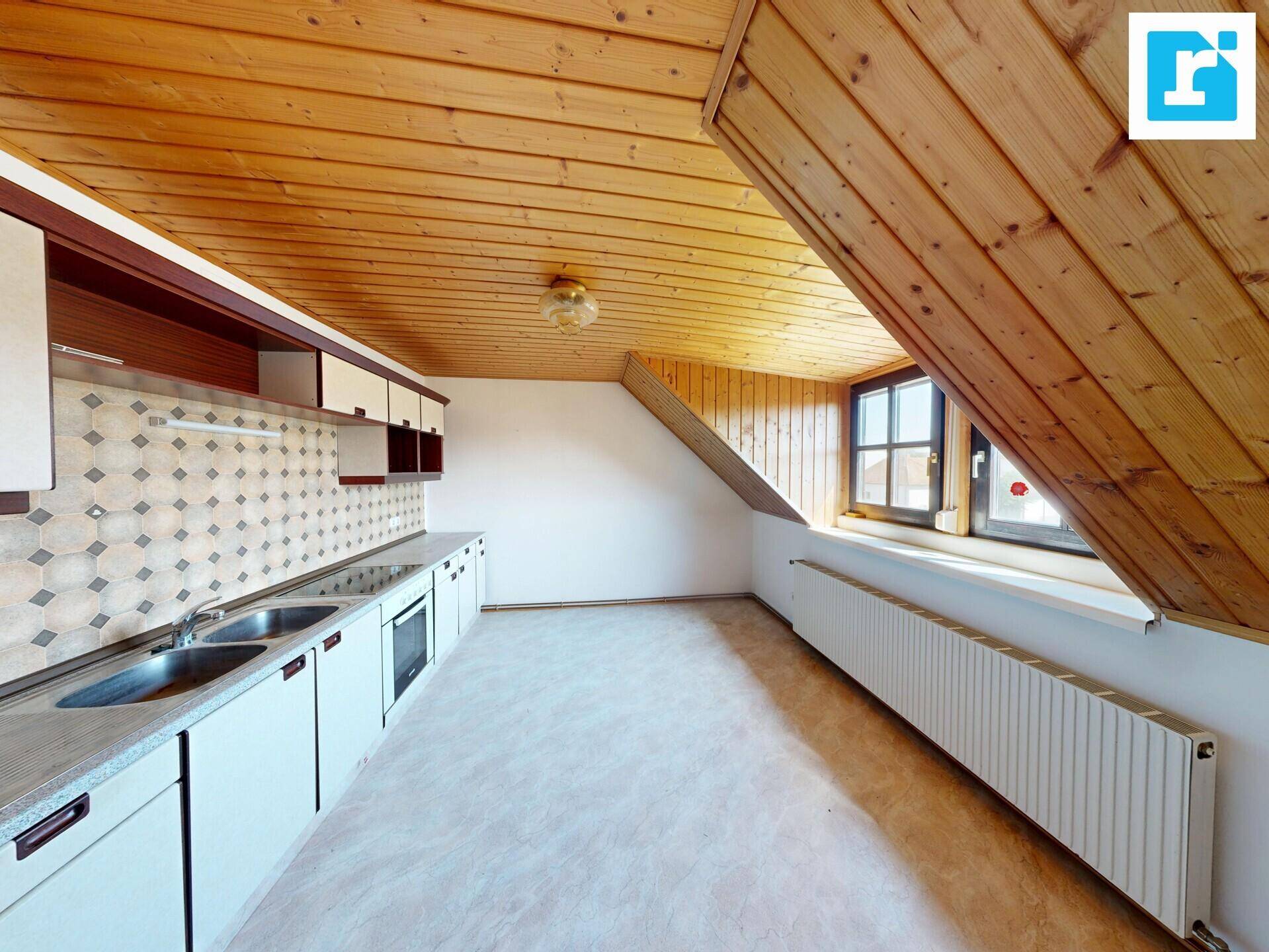 Helle Dachgeschossküche mit Holzdecke, weißen Schränken und einem Fenster.