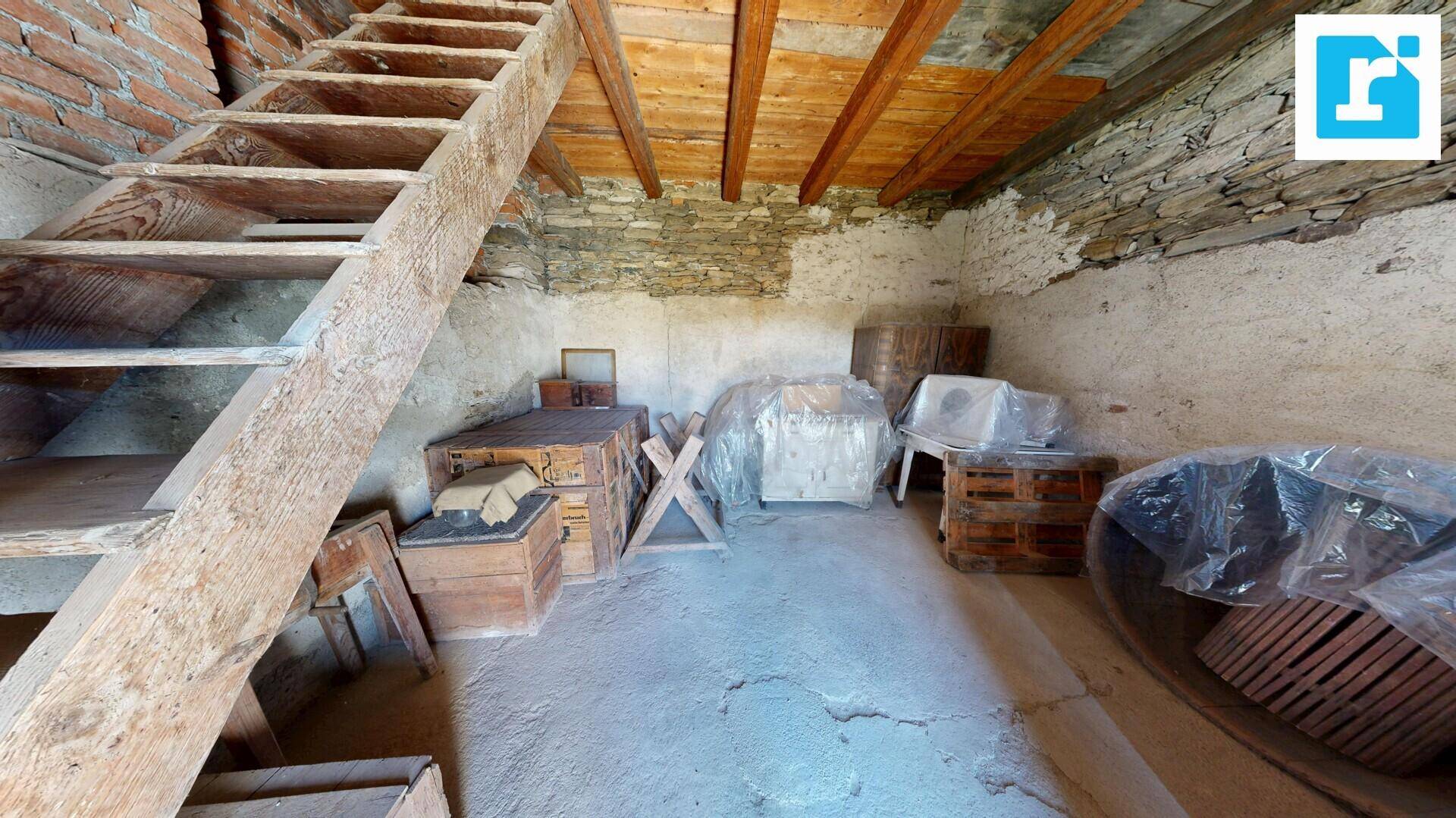 Alter Kellerraum mit Holzbalken, Ziegelwänden und einer einfachen Holztreppe.