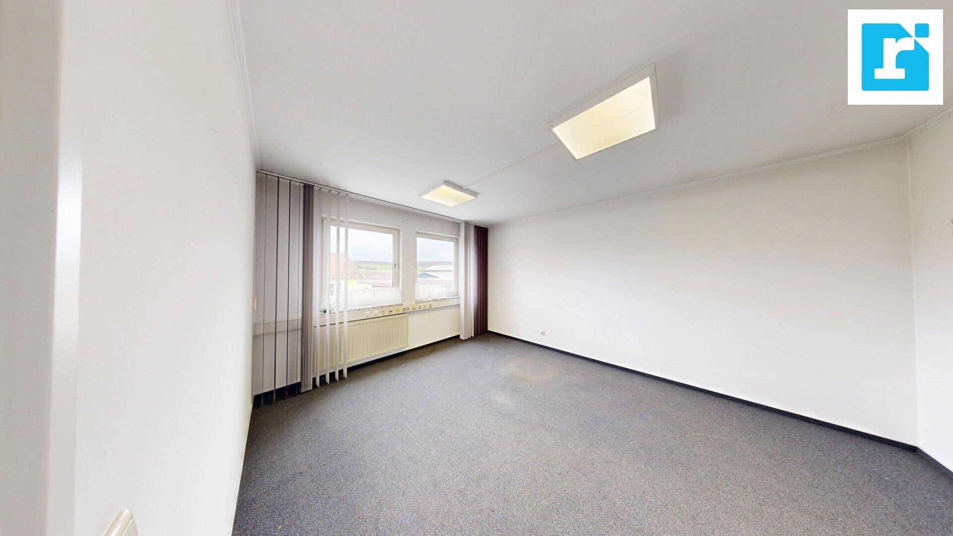 Helles, leeres Büro mit Teppichboden und Fenstern, bereit zur individuellen Einrichtung.