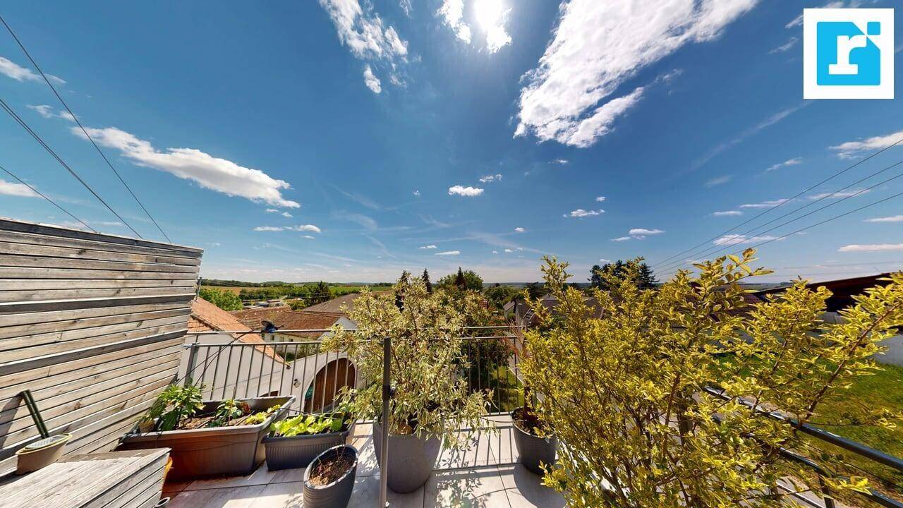 Sonnige Terrasse mit Topfpflanzen und einem weiten, grünen Blick über die ländliche Umgebung.