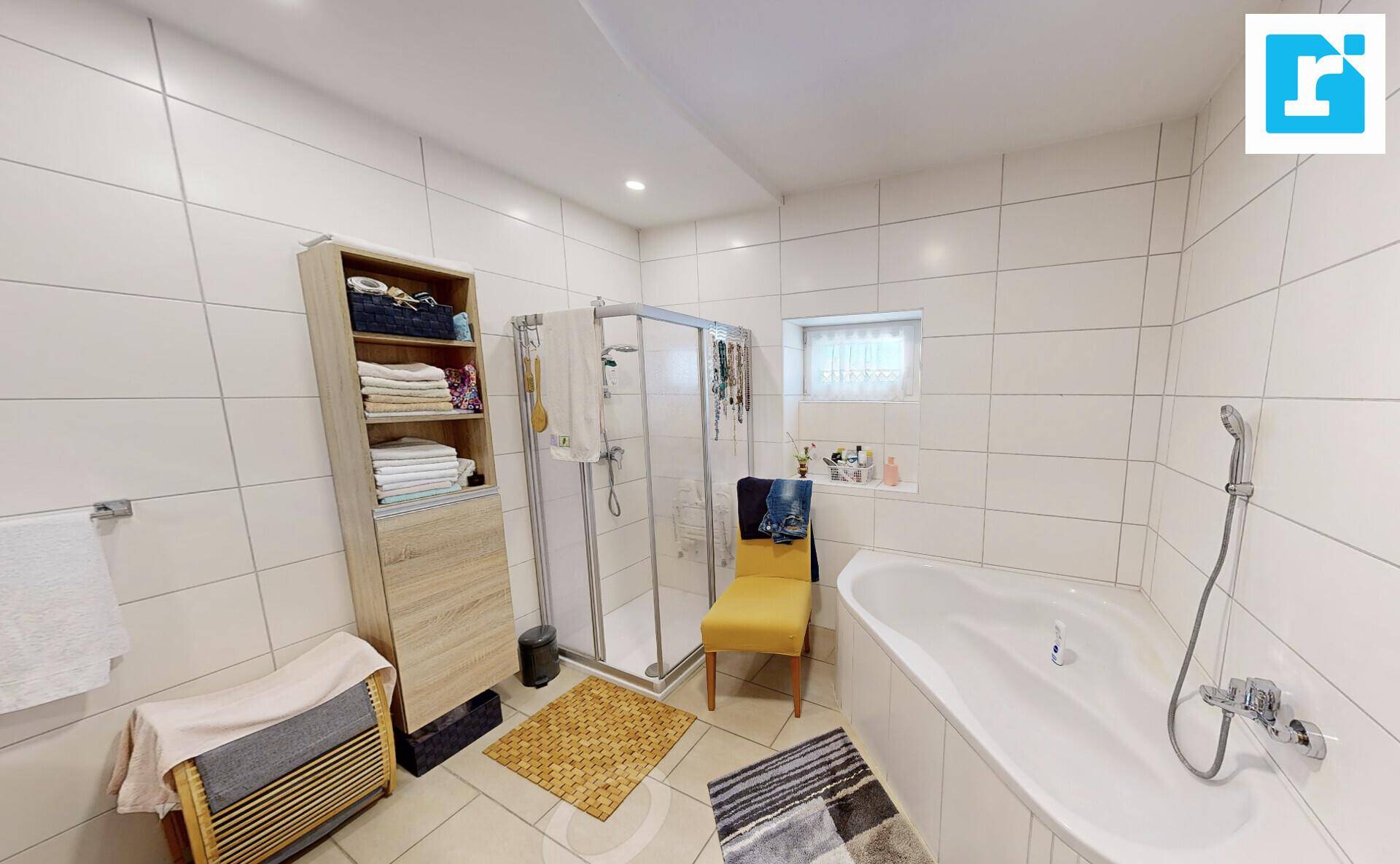 Modern gefliestes Badezimmer mit Badewanne, Duschkabine und kleinem Fenster.
