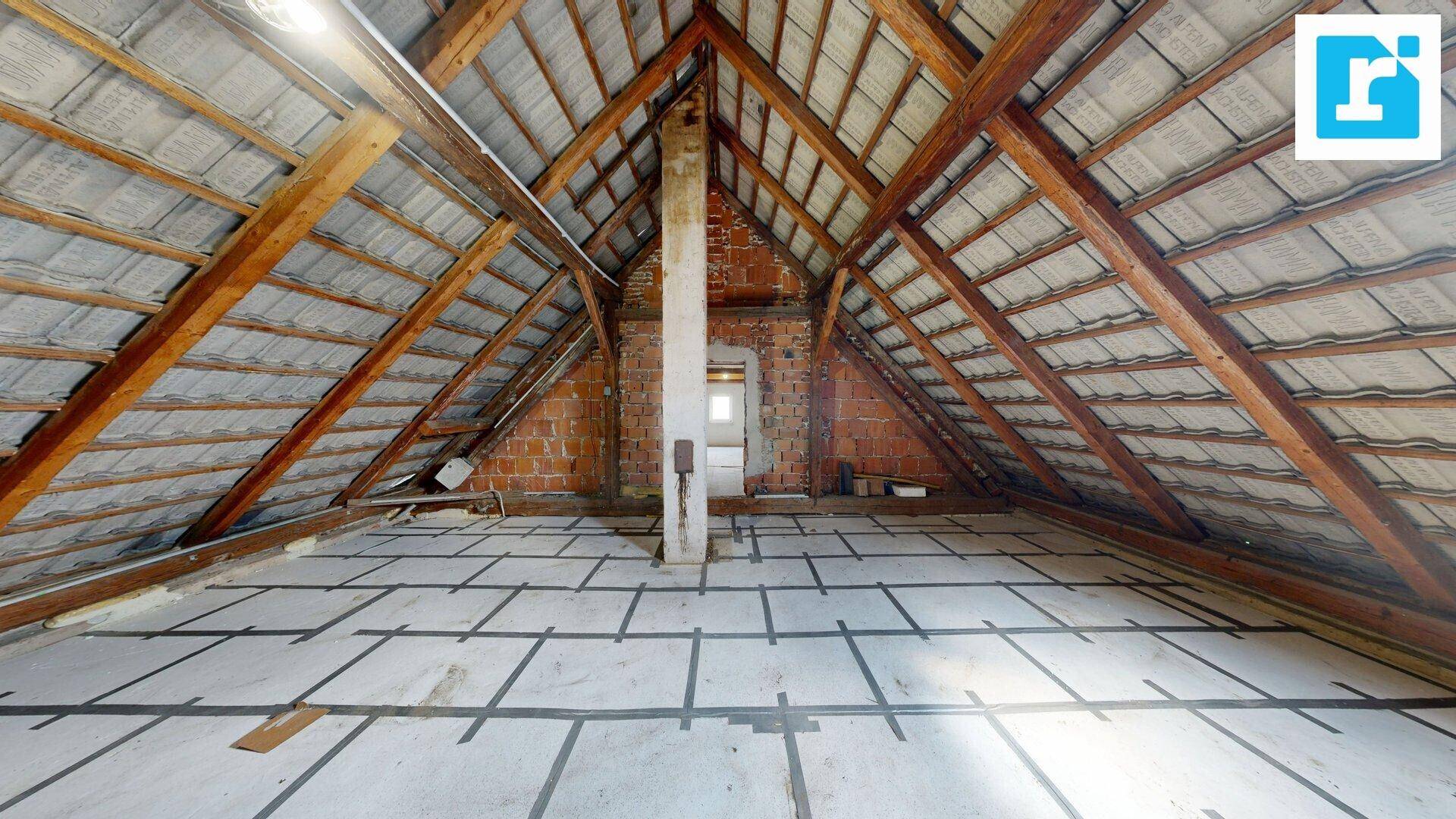 Weitläufiger Dachboden mit sichtbarem Holzdachstuhl und Ziegelwänden, ideal für Umbau.