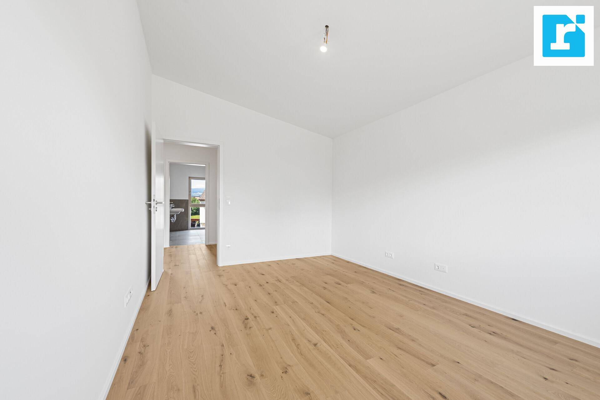 Geräumiges Schlafzimmer mit Parkettboden und Zugang zu einem angrenzenden Badezimmer.