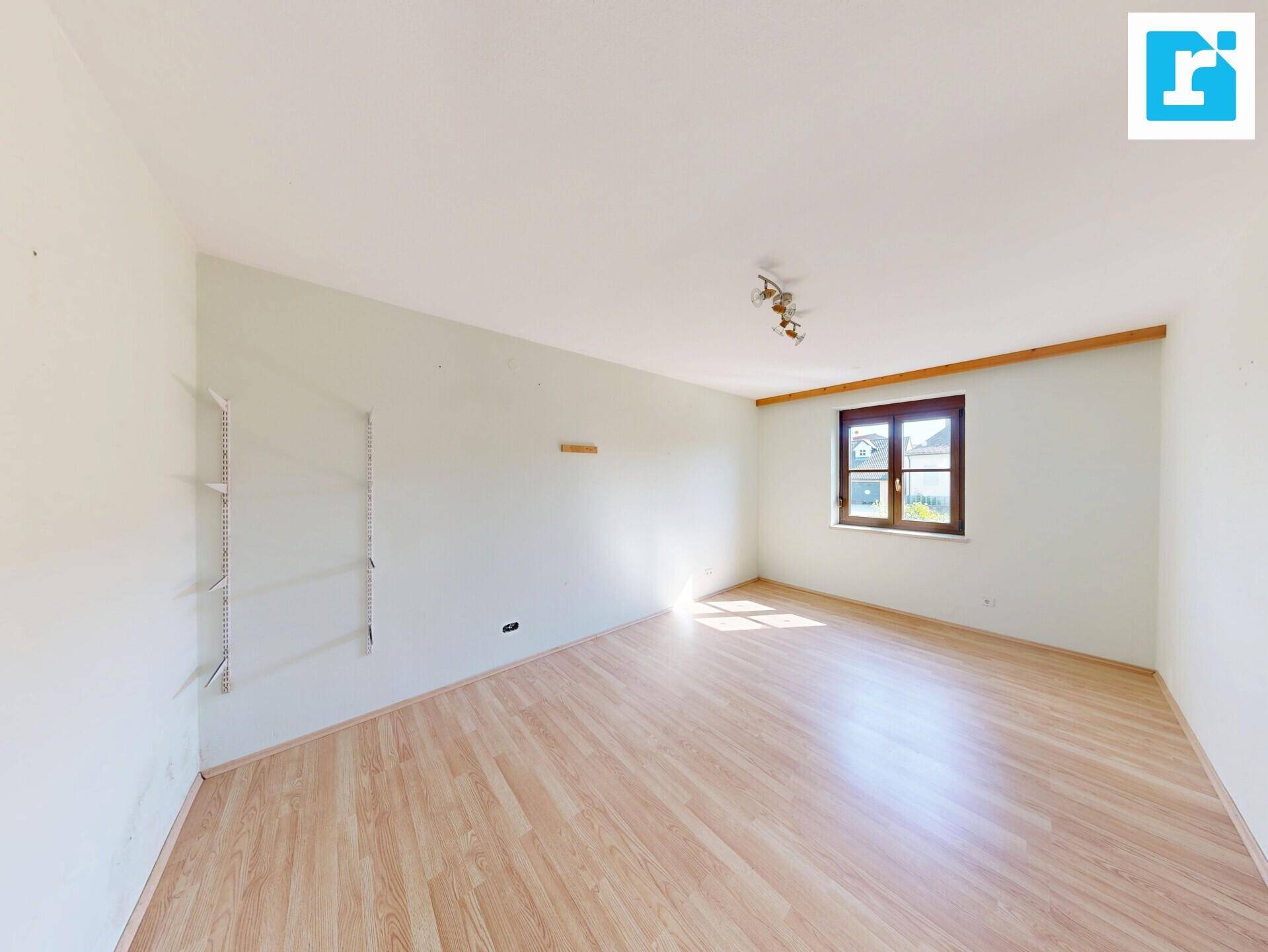Helles Zimmer mit Laminatboden, Wandregalen und einem Fenster für natürliche Belichtung.