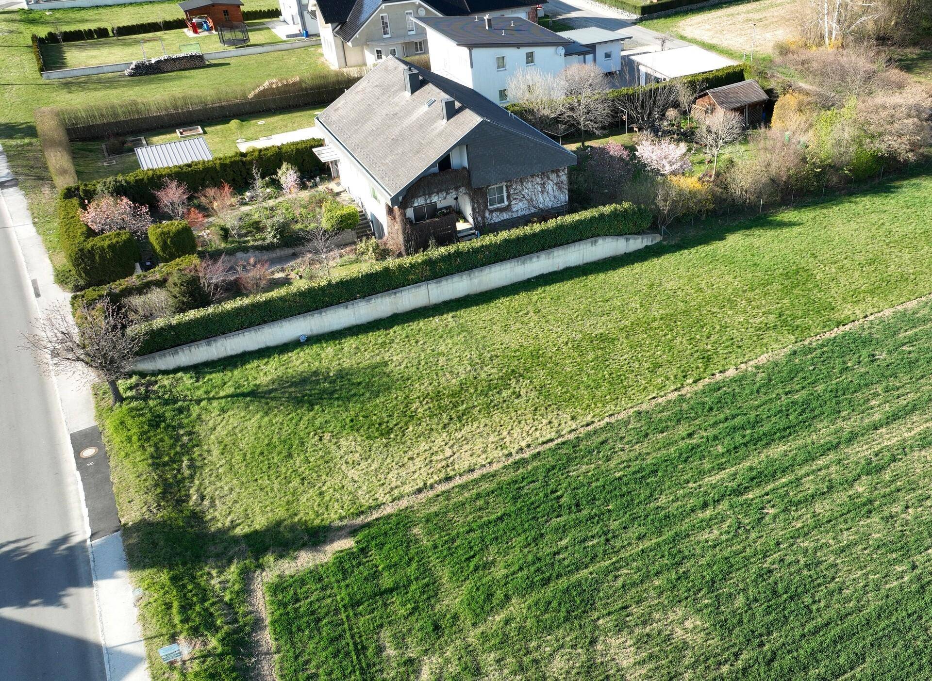 Luftaufnahme eines Einfamilienhauses mit Garten und angrenzenden grünen Feldern in ländlicher Umgebung.