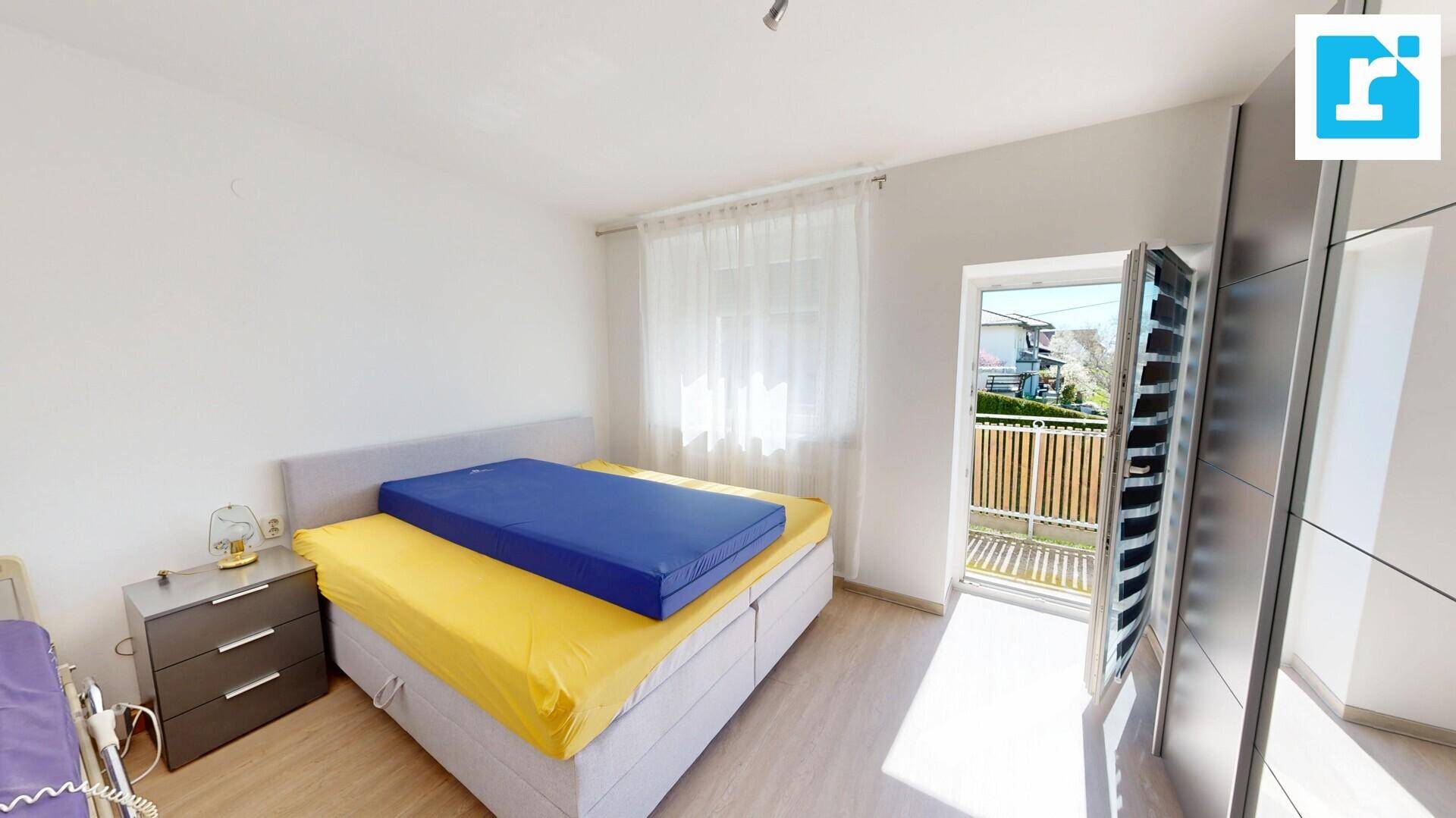 Helles Schlafzimmer mit Bett, Kleiderschrank und direktem Zugang zum Balkon.