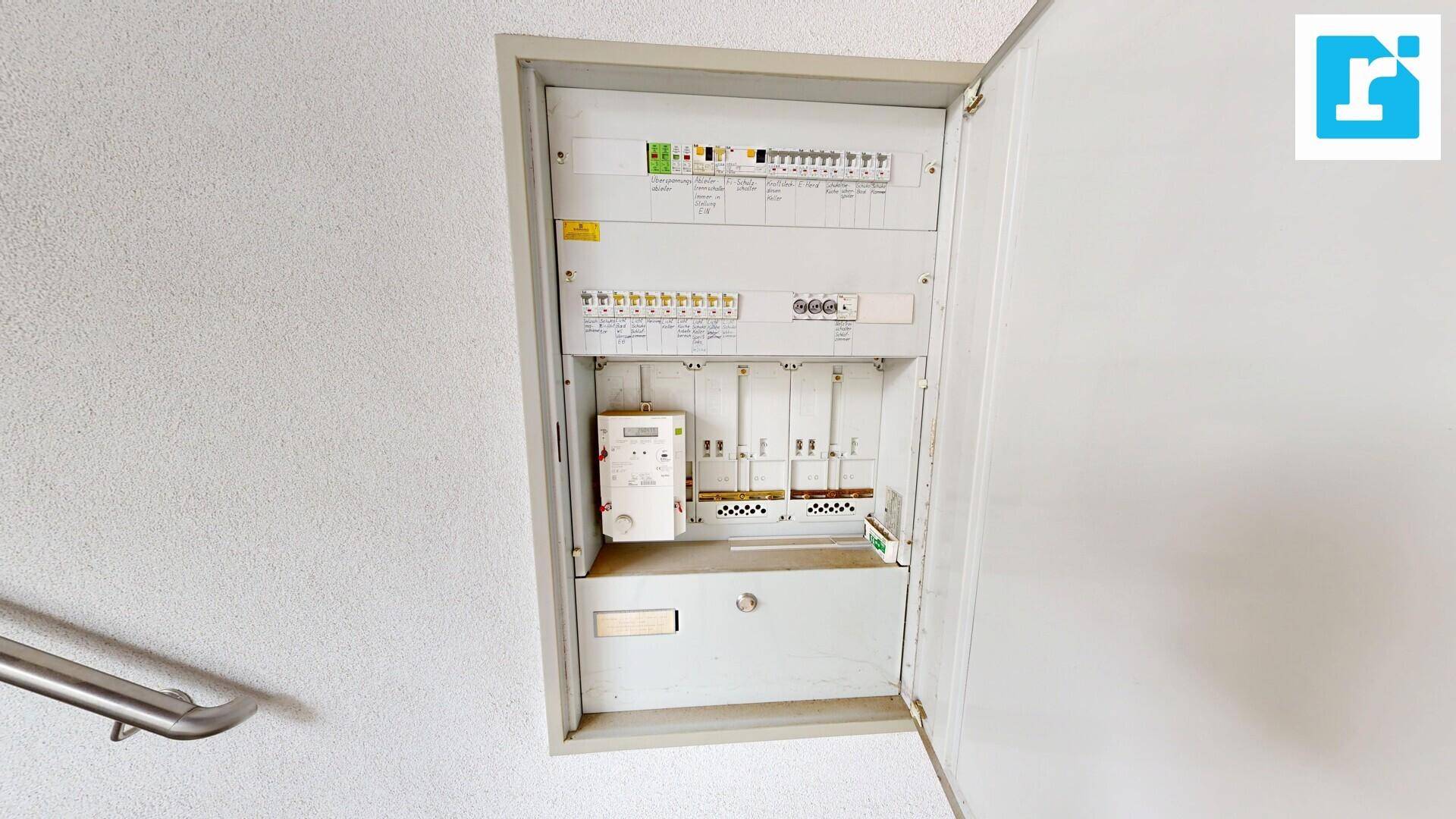 Offener Sicherungskasten mit Stromzähler und elektrischen Installationen.