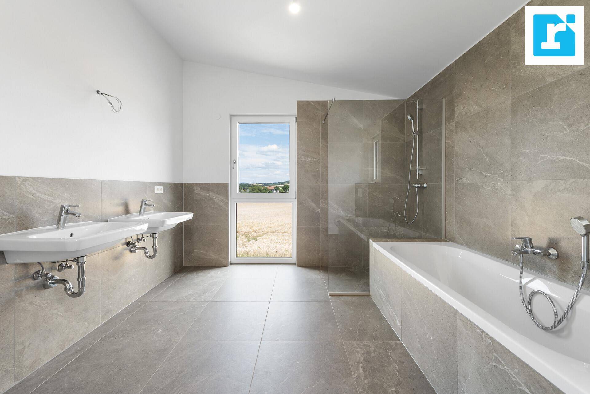 Helles und geräumiges Badezimmer mit zwei Waschbecken, Badewanne und bodengleicher Dusche.