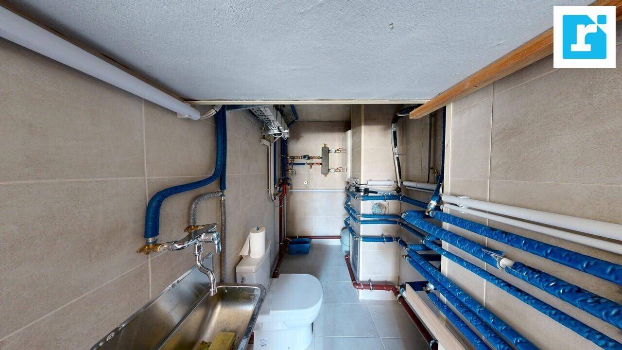 Funktionaler Hauswirtschaftsraum im Keller mit sichtbaren Installationen, Waschbecken und Toilette.
