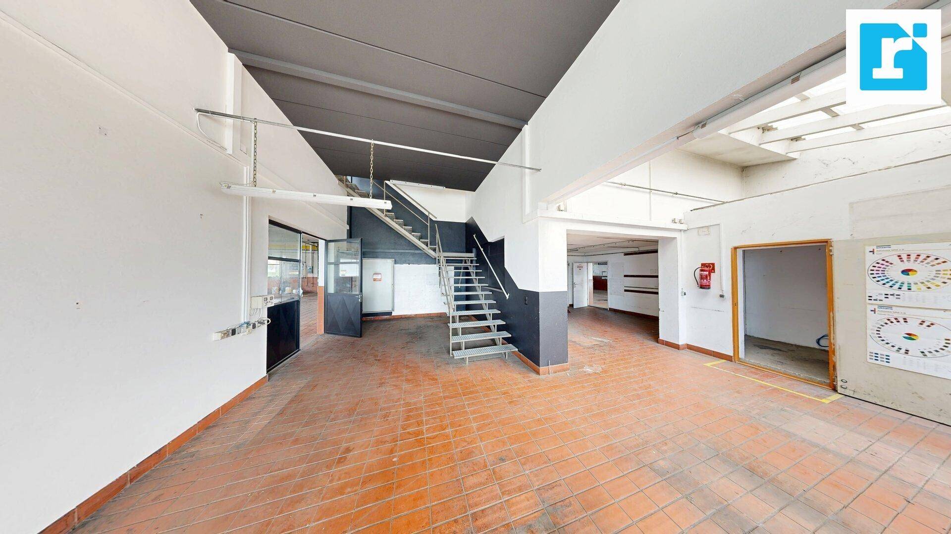 Werkstattbereich mit Terrakotta-Fliesenboden und Treppe zum oberen Bereich, funktional gestaltet.