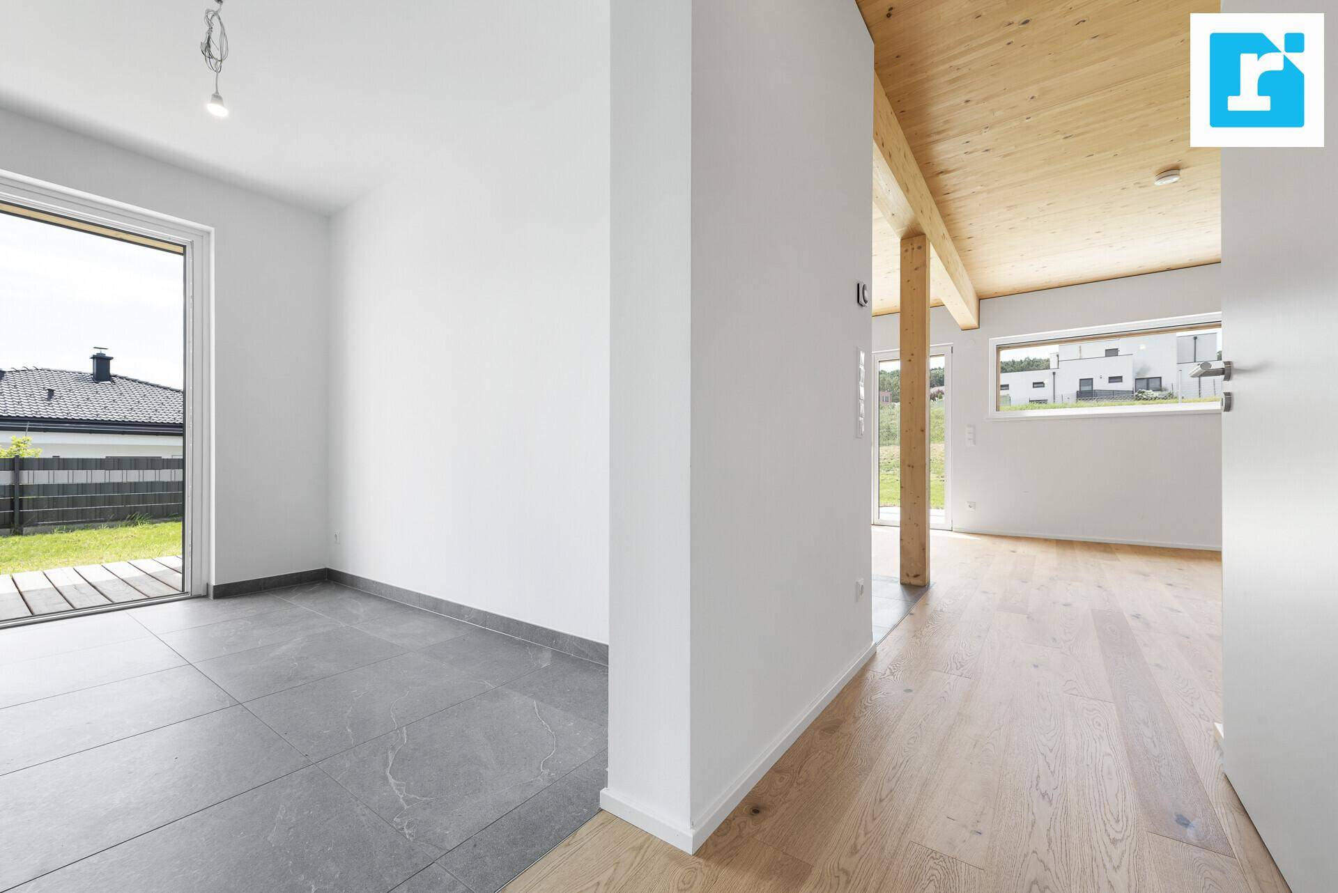 Übergangsbereich mit Parkettboden und Fliesen, hell durch große Fenster.