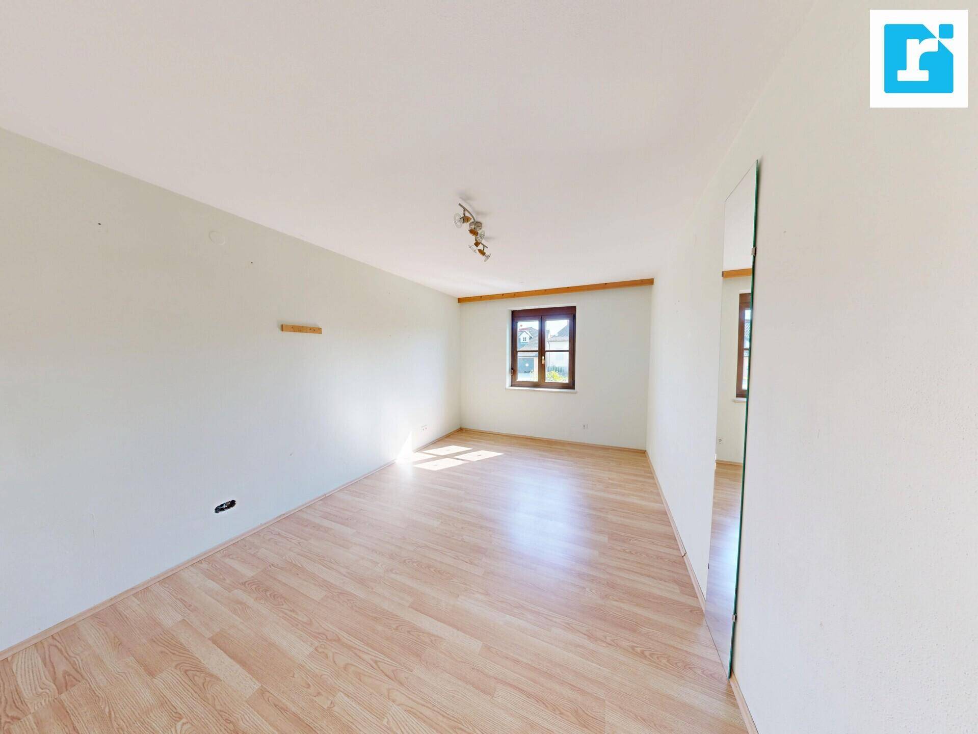 Geräumiges Zimmer mit Laminatboden und einem Fenster, das viel Tageslicht hereinlässt.