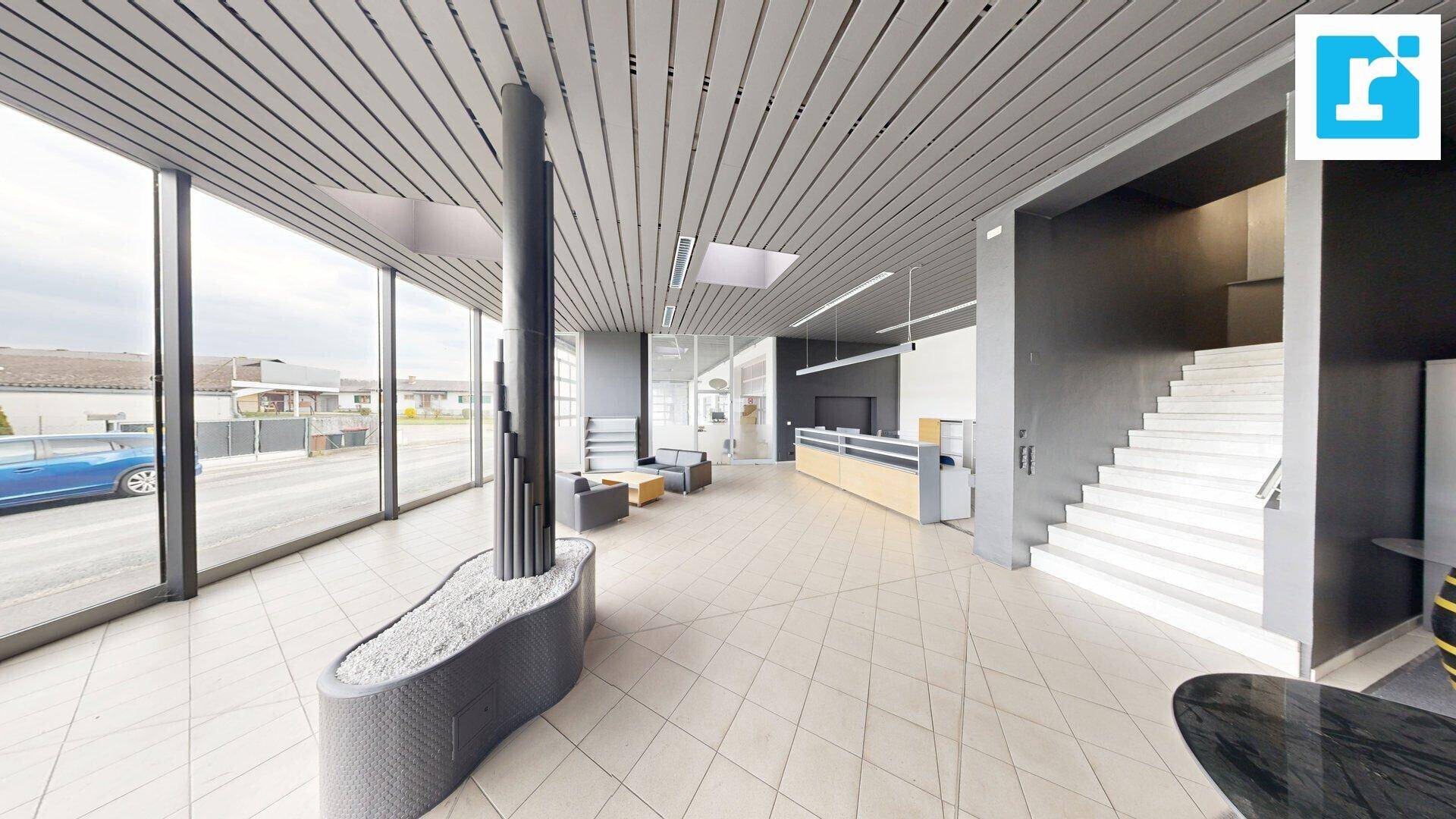 Heller Empfangsbereich mit Treppe, Fliesenboden und großen Fensterfronten, einladend gestaltet.