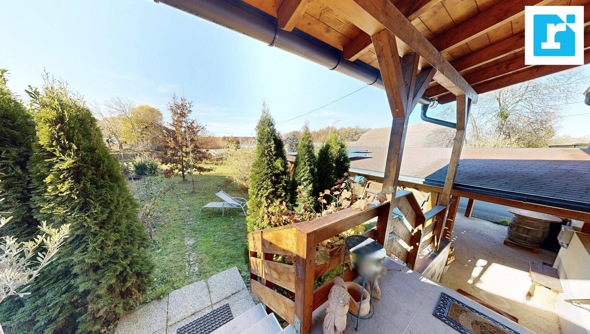 Überdachte Terrasse mit Holzkonstruktion und Blick in den grünen Garten.