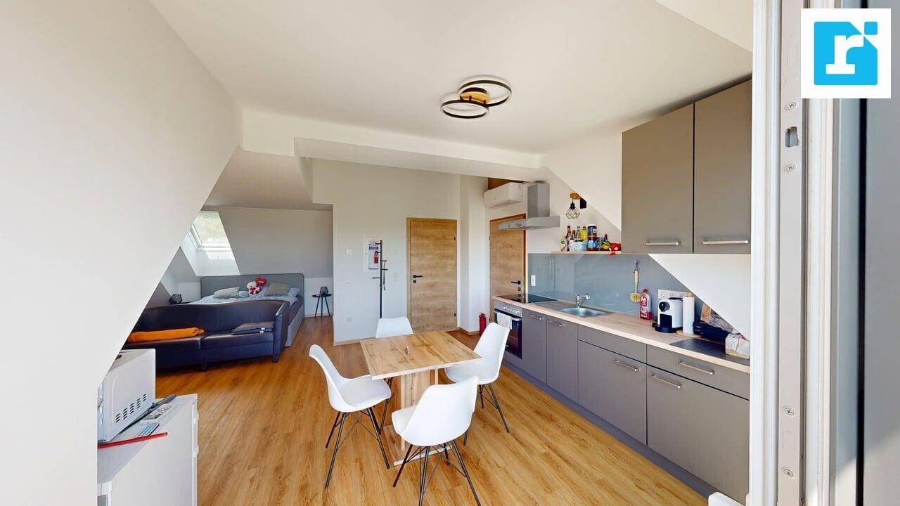 Offene Dachgeschosswohnung mit integrierter Küche, Essbereich und Schlafbereich unter schrägen Decken.