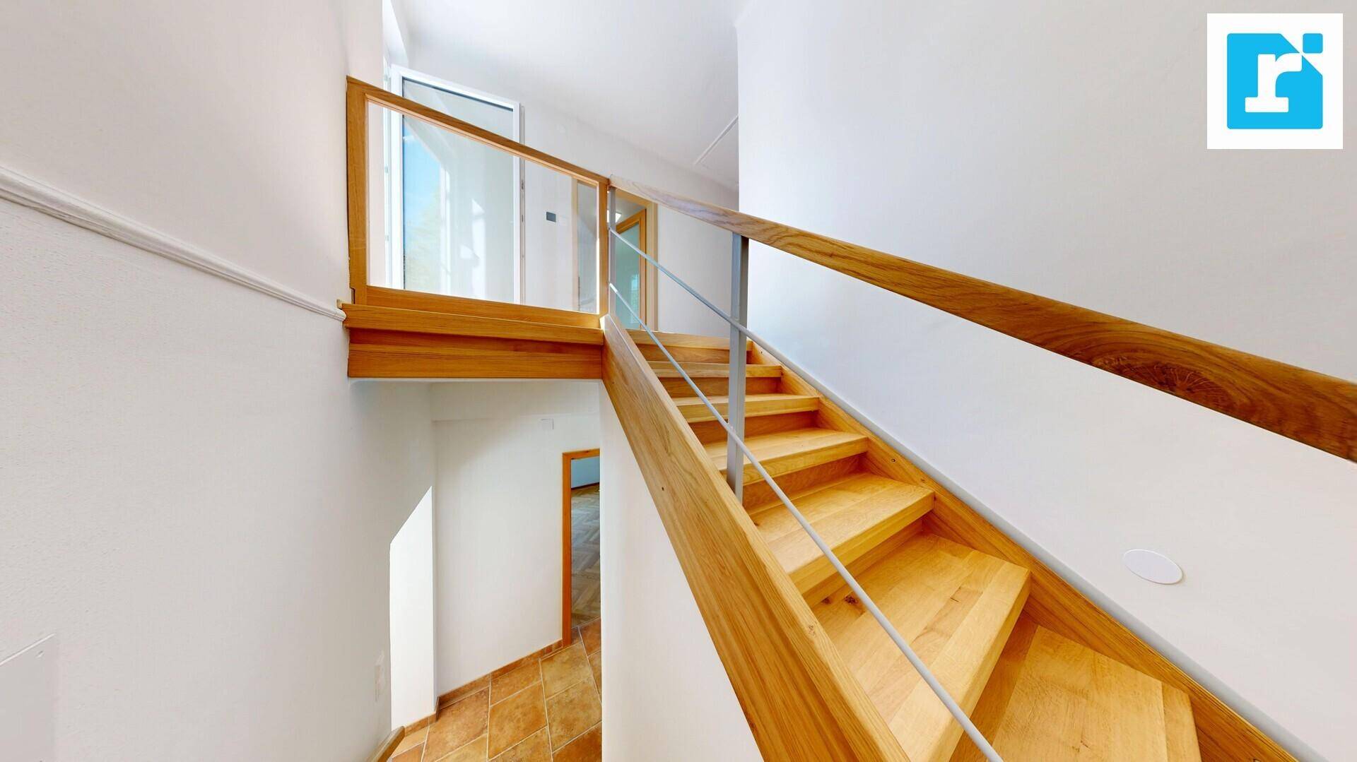 Elegante Holztreppe mit Glasgeländer führt in die obere Etage, heller Flur.