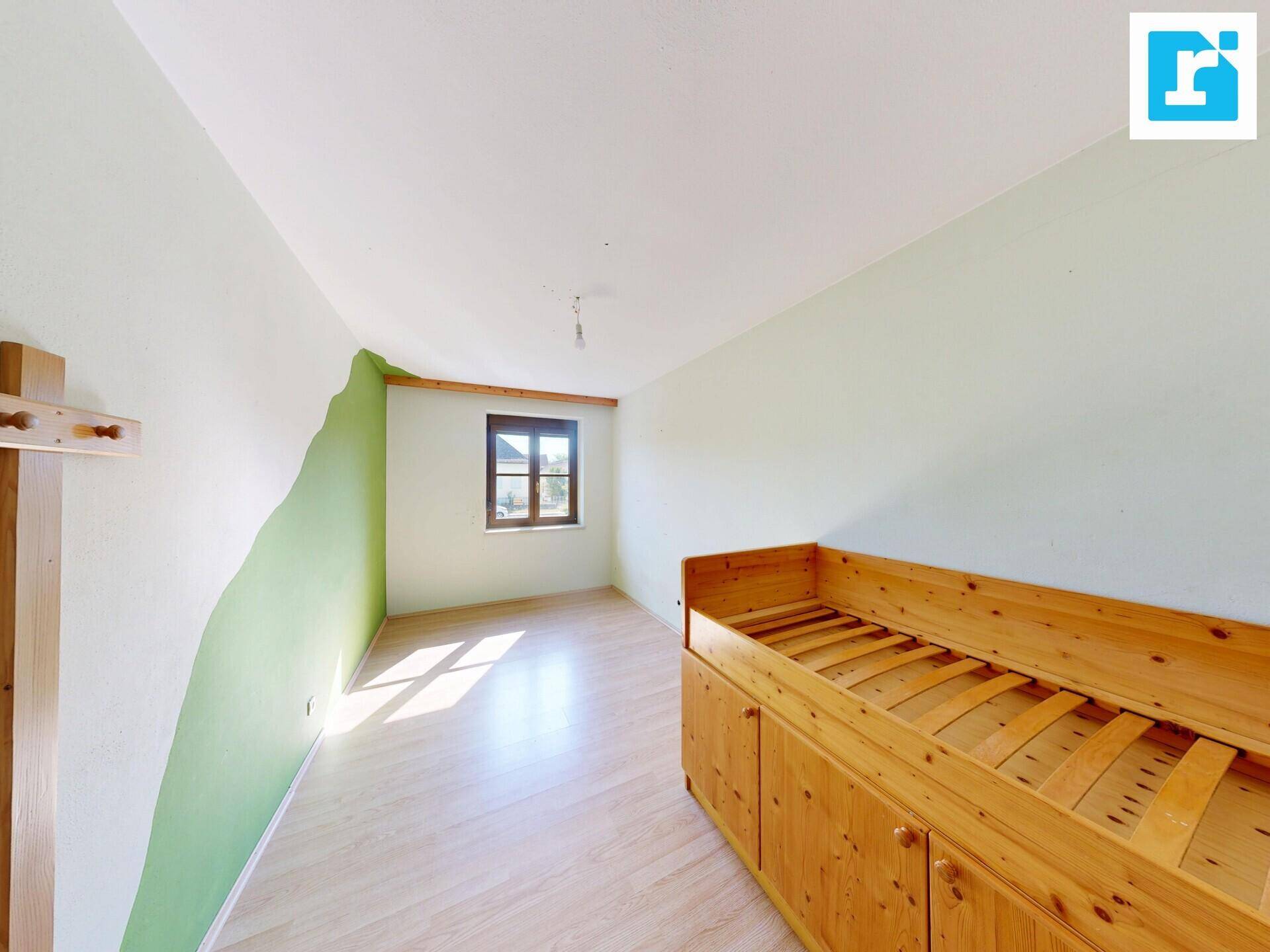 Helles Schlafzimmer mit Holzbettrahmen, Laminatboden und einem Fenster für natürliches Licht.