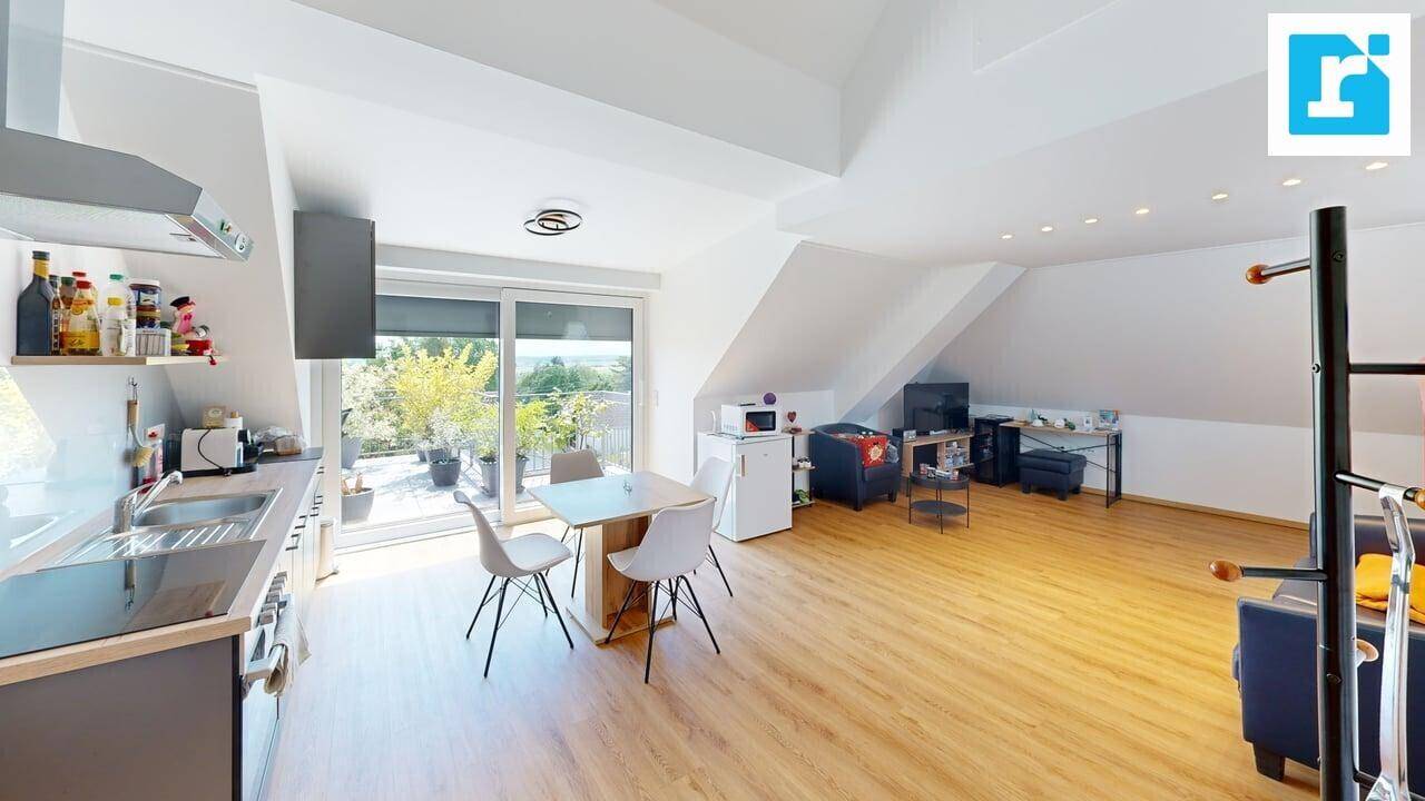 Helle Dachgeschosswohnung mit moderner Küche, Essbereich und Zugang zu einer Außenterrasse.
