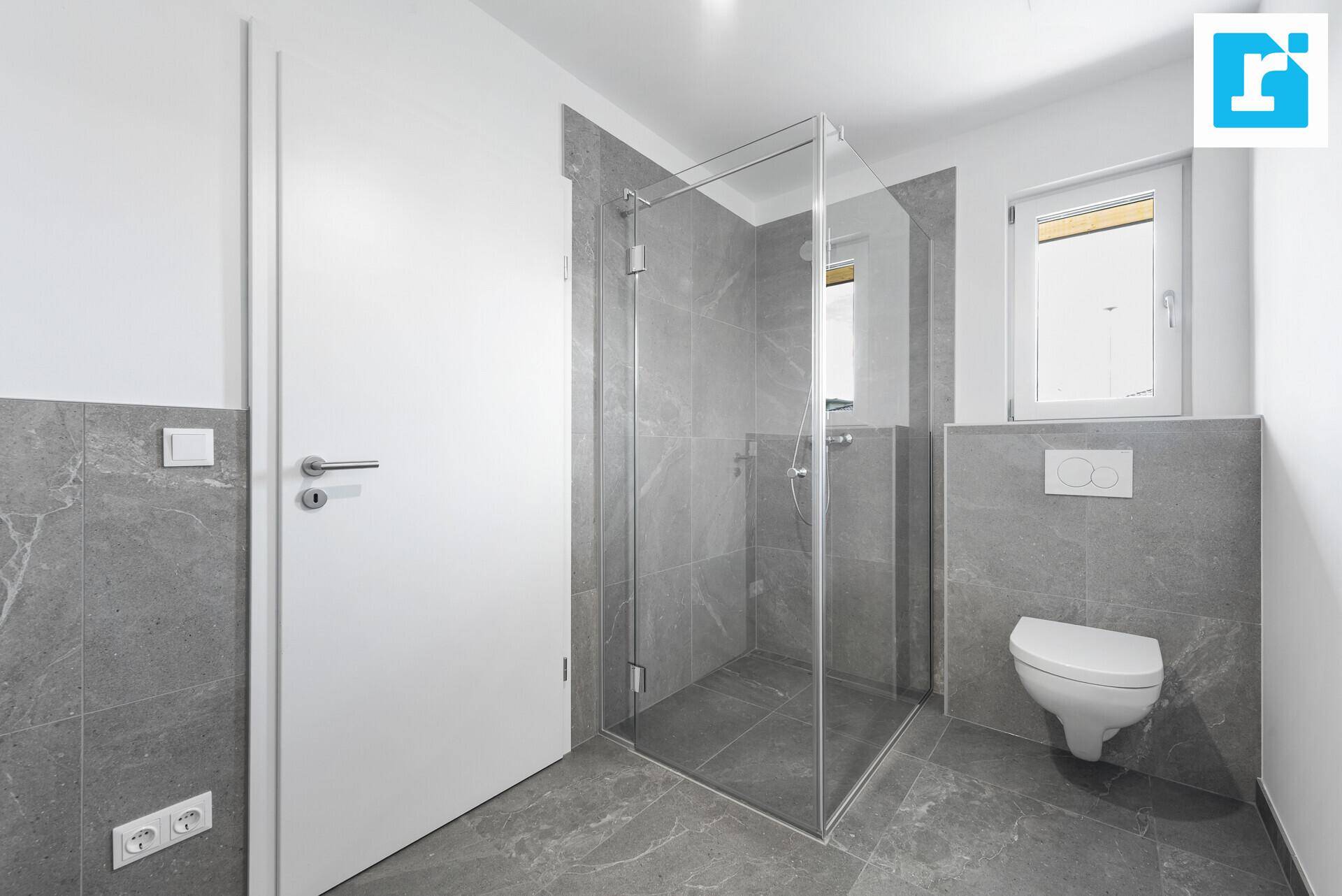 Modernes Badezimmer mit Duschkabine, Wand-WC und Fenster für Tageslicht.