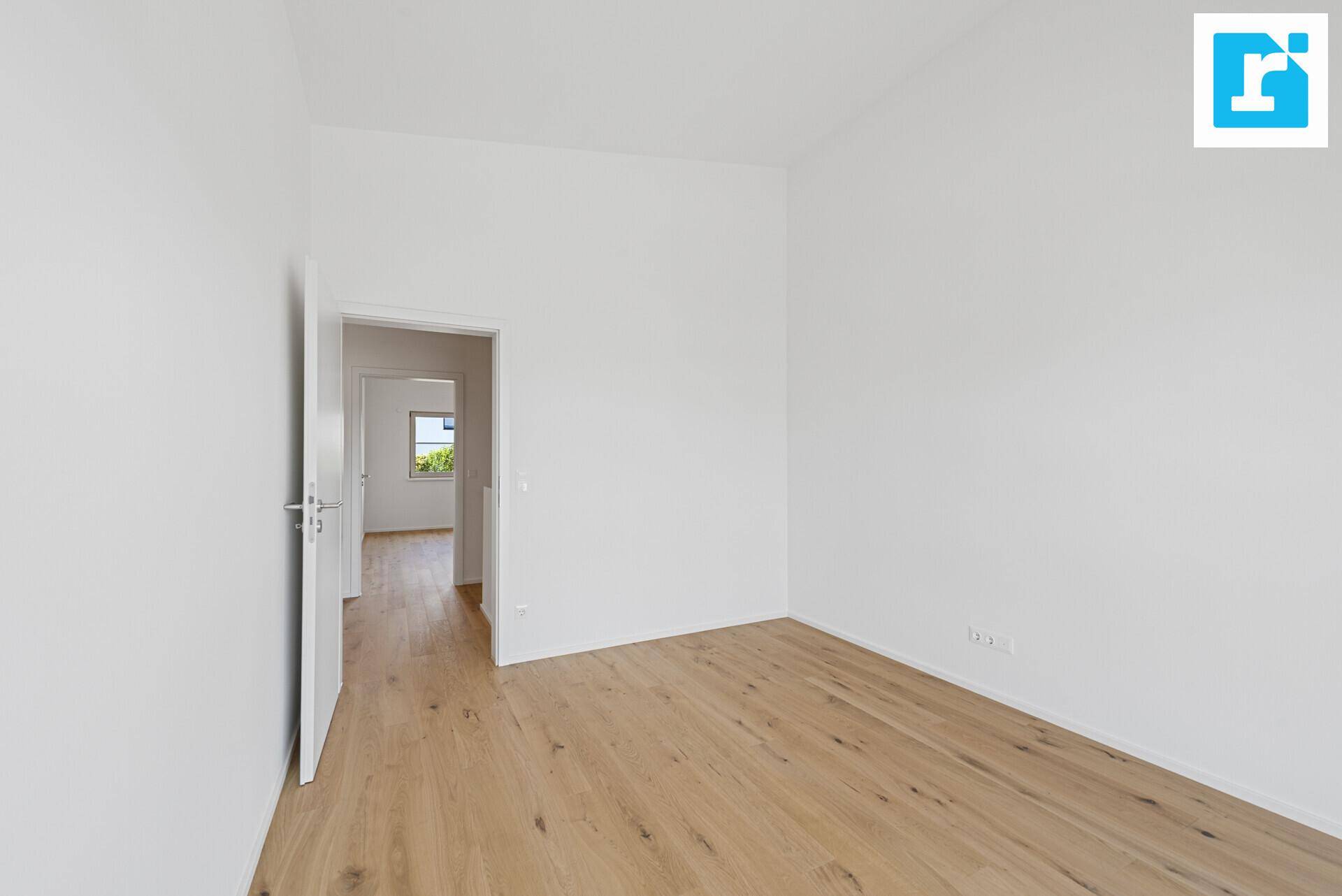 Geräumiges Schlafzimmer mit Parkettboden und Zugang zu einem weiteren Raum.
