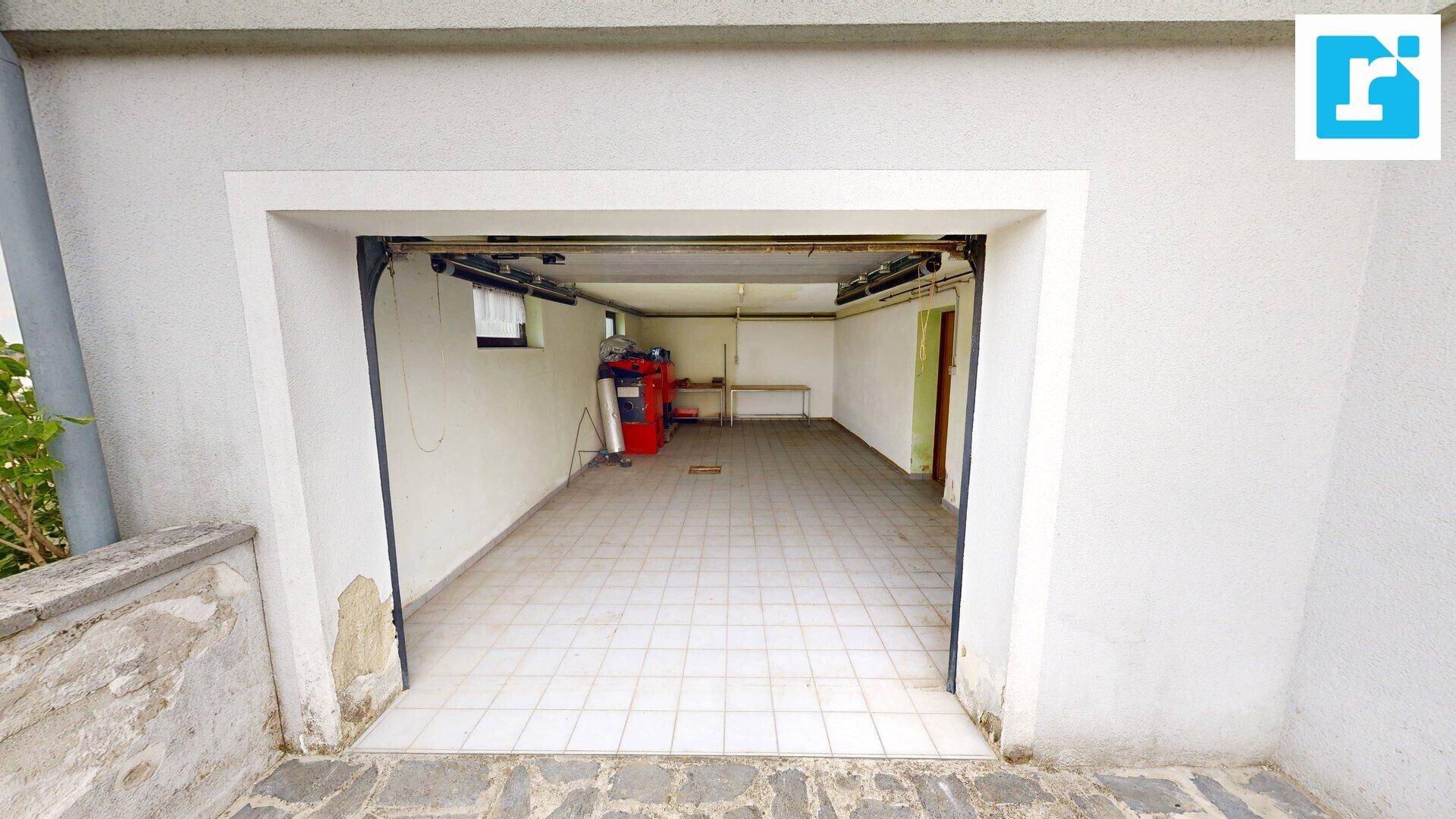 Leere Garage mit gefliestem Boden und einem roten Gerät im Hintergrund, bereit zur Nutzung.