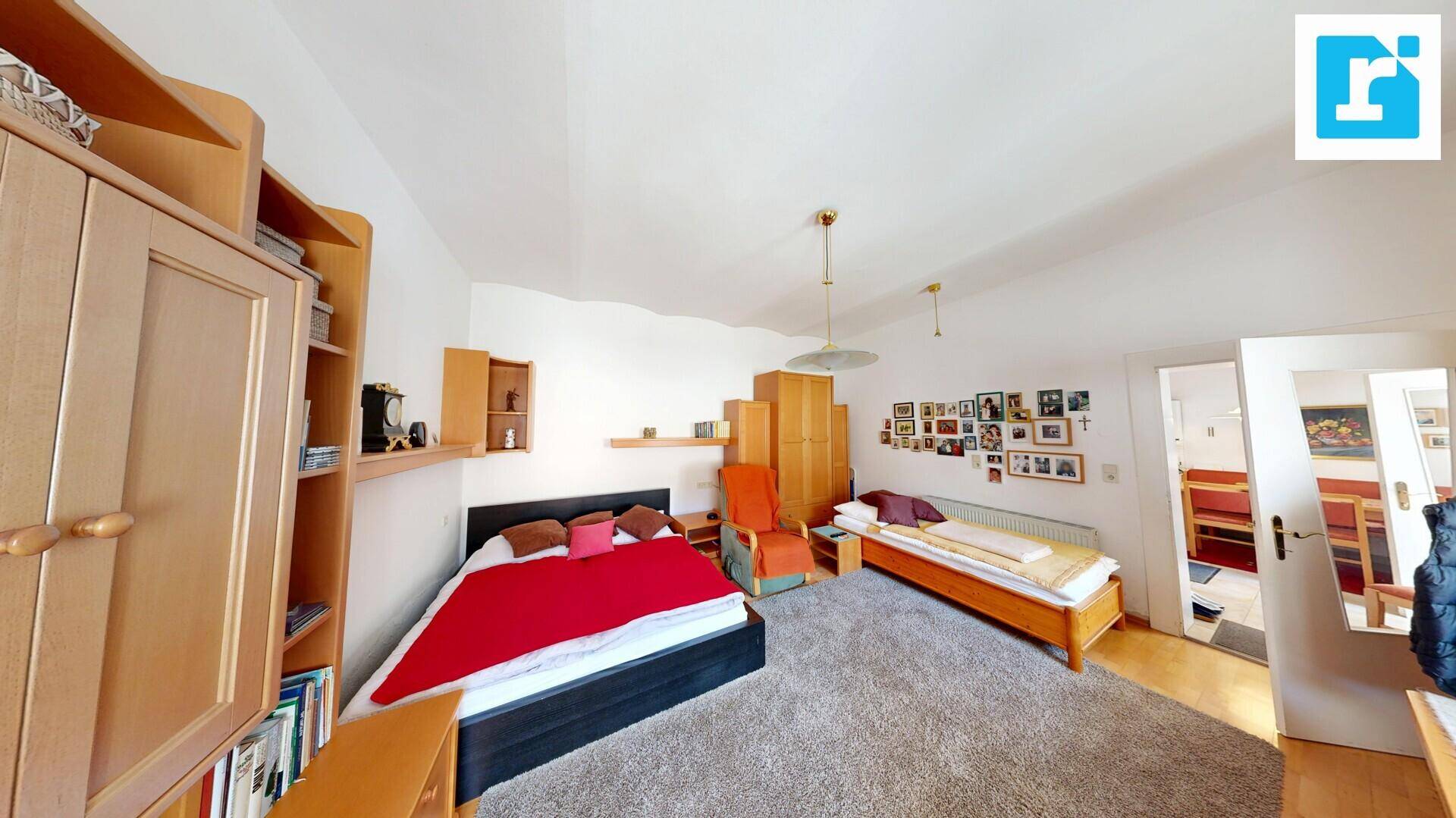 Geräumiges Schlafzimmer mit Teppichboden, zwei Betten und Holzmöbeln in hellem Ambiente.