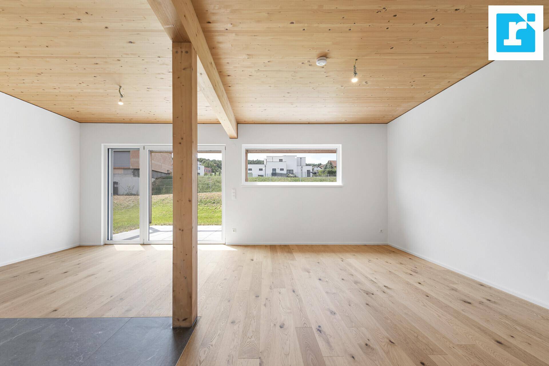 Heller Wohnbereich mit Holzbalkendecke, Parkettboden und weitem Ausblick.