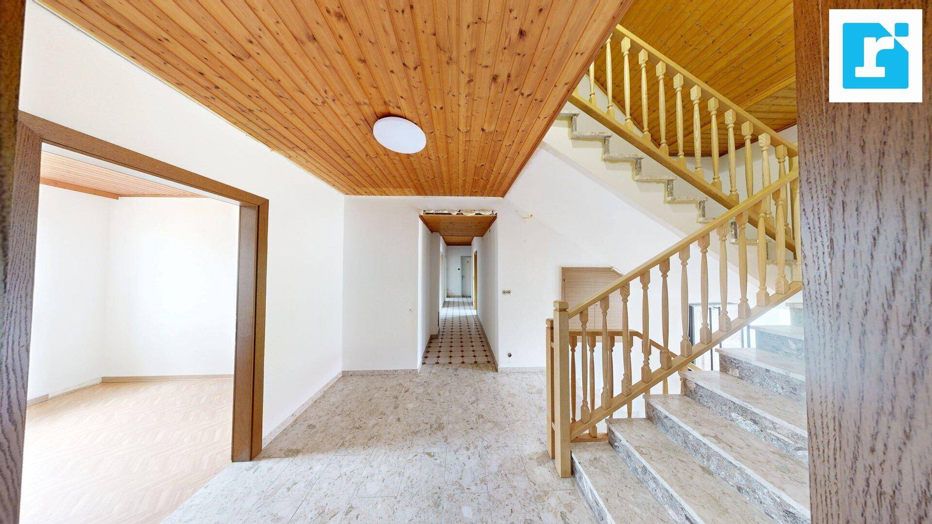 Eingangsbereich mit Marmorboden, Holzdecke und Treppe, die in die obere Etage führt.