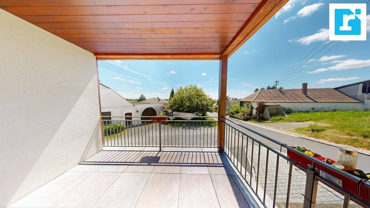 Überdachter Balkon mit Holzdecke, Fliesenboden und Blick auf die Straße und umliegende Häuser.