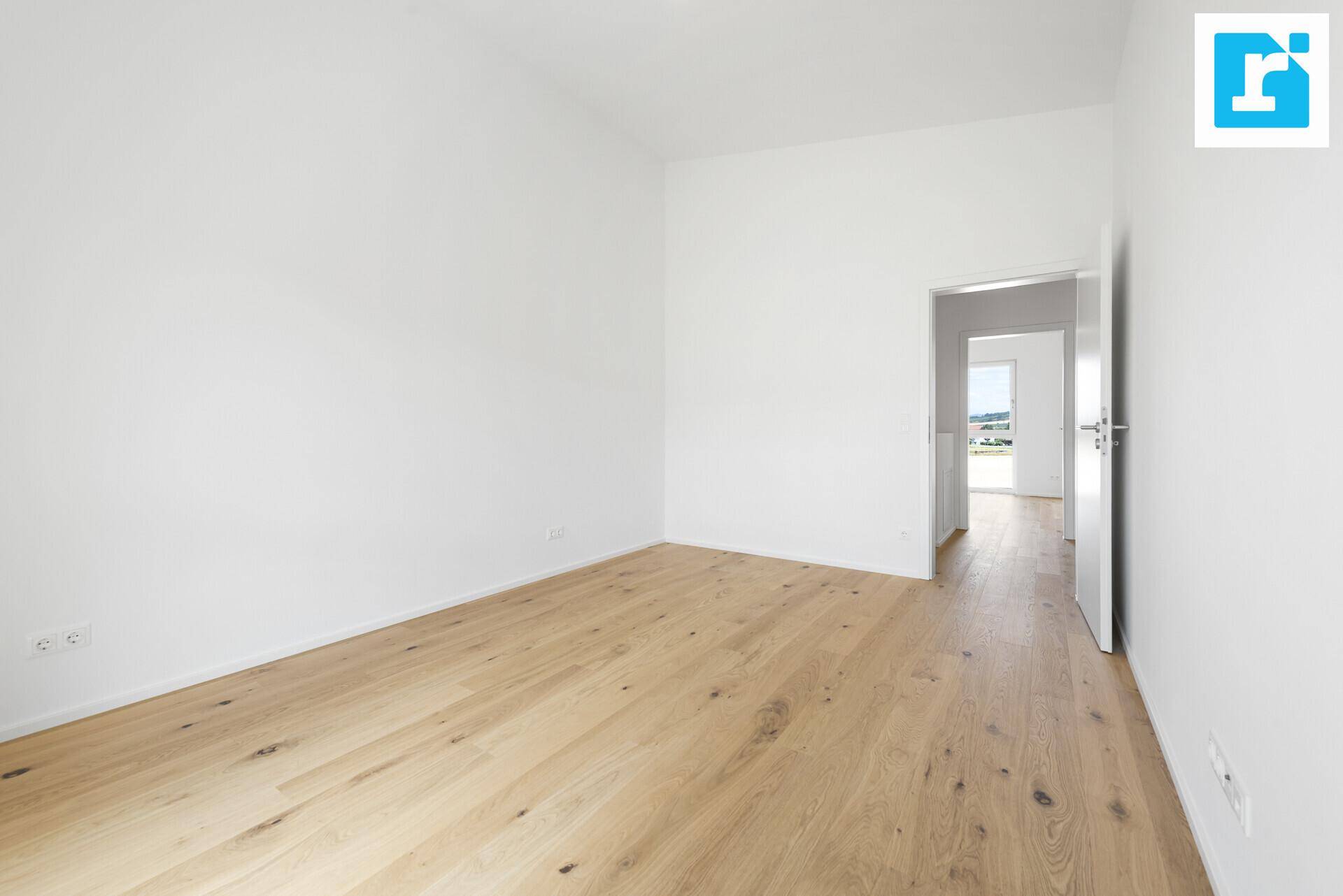 Leeres Zimmer mit hellem Holzboden und weiß gestrichenen Wänden, bereit zur individuellen Gestaltung.