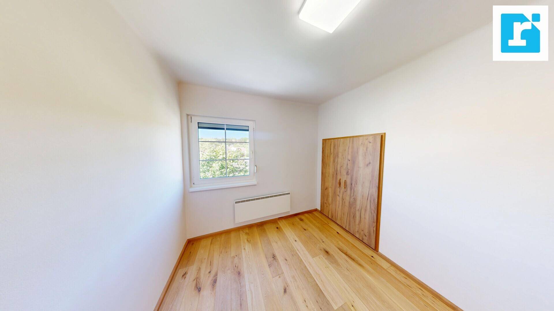 Helles Schlafzimmer mit Holzdielenboden, Fenster und integriertem Holzschrank.