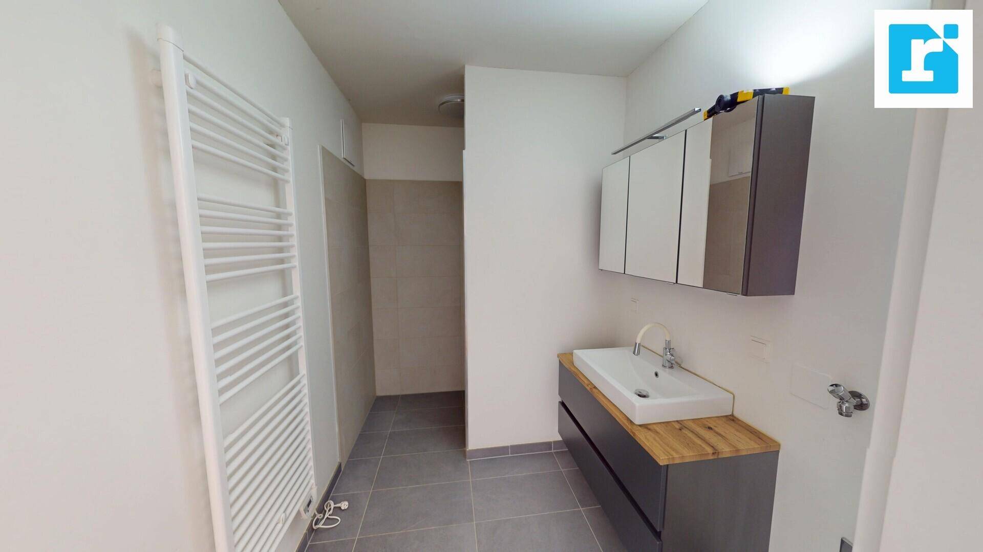 Modernes Badezimmer mit Einzelwaschbecken, Holzplatte und beheiztem Handtuchhalter.