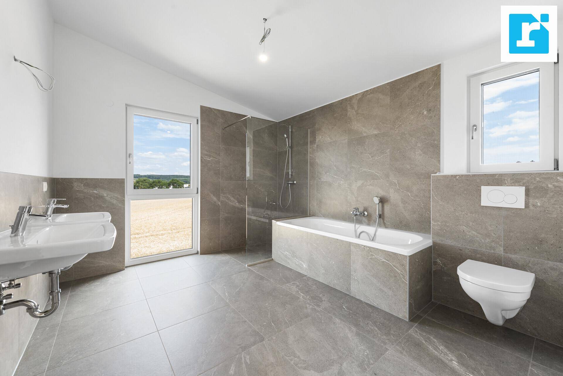Modernes Badezimmer mit Doppelwaschbecken, Badewanne, Dusche und großem Fenster mit Ausblick.