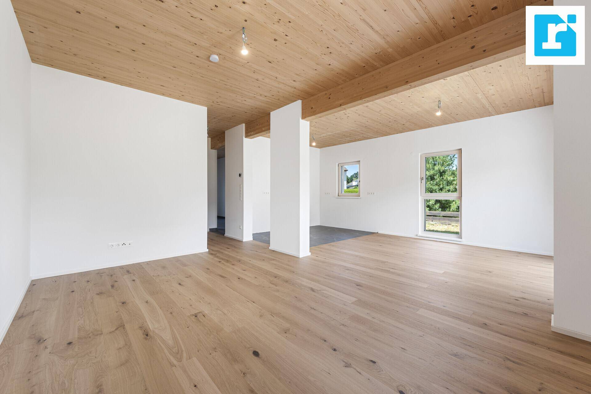Weitläufiger Wohnbereich mit Holzbalkendecke, Parkettboden und viel natürlichem Licht.