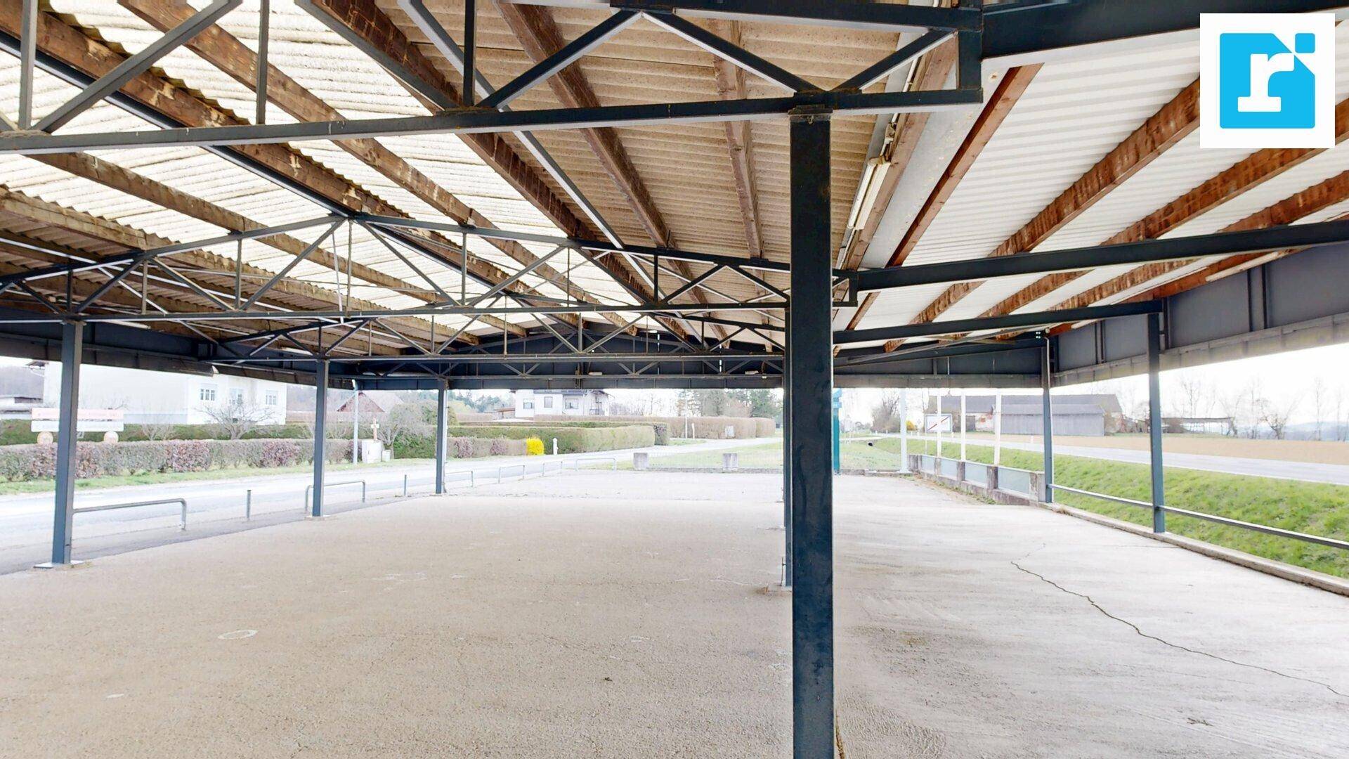 Überdachter Parkbereich mit Metallkonstruktion, bietet Schutz für Fahrzeuge vor Witterungseinflüssen.