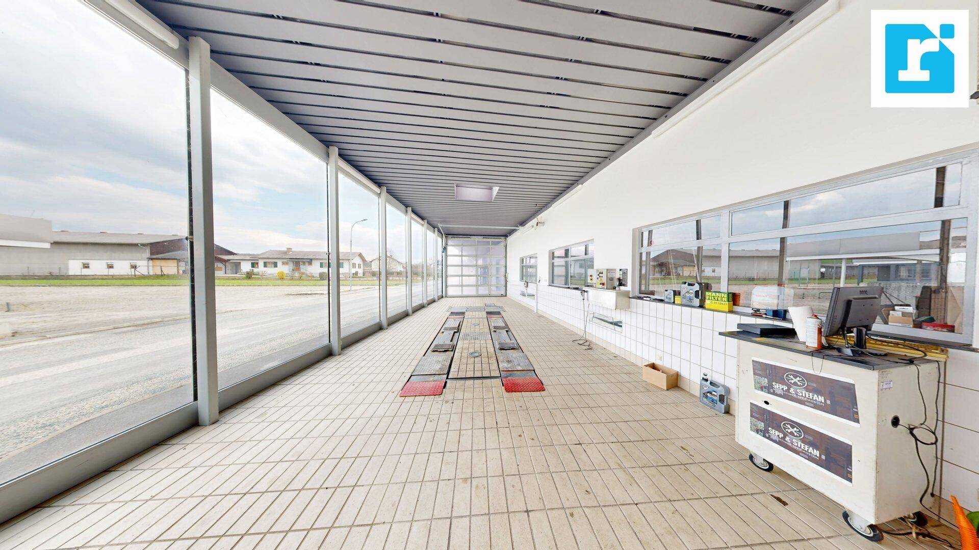 Werkstatt mit Fliesenboden, großen Fensterfronten und Hebebühnen, ideal für Fahrzeugreparaturen.
