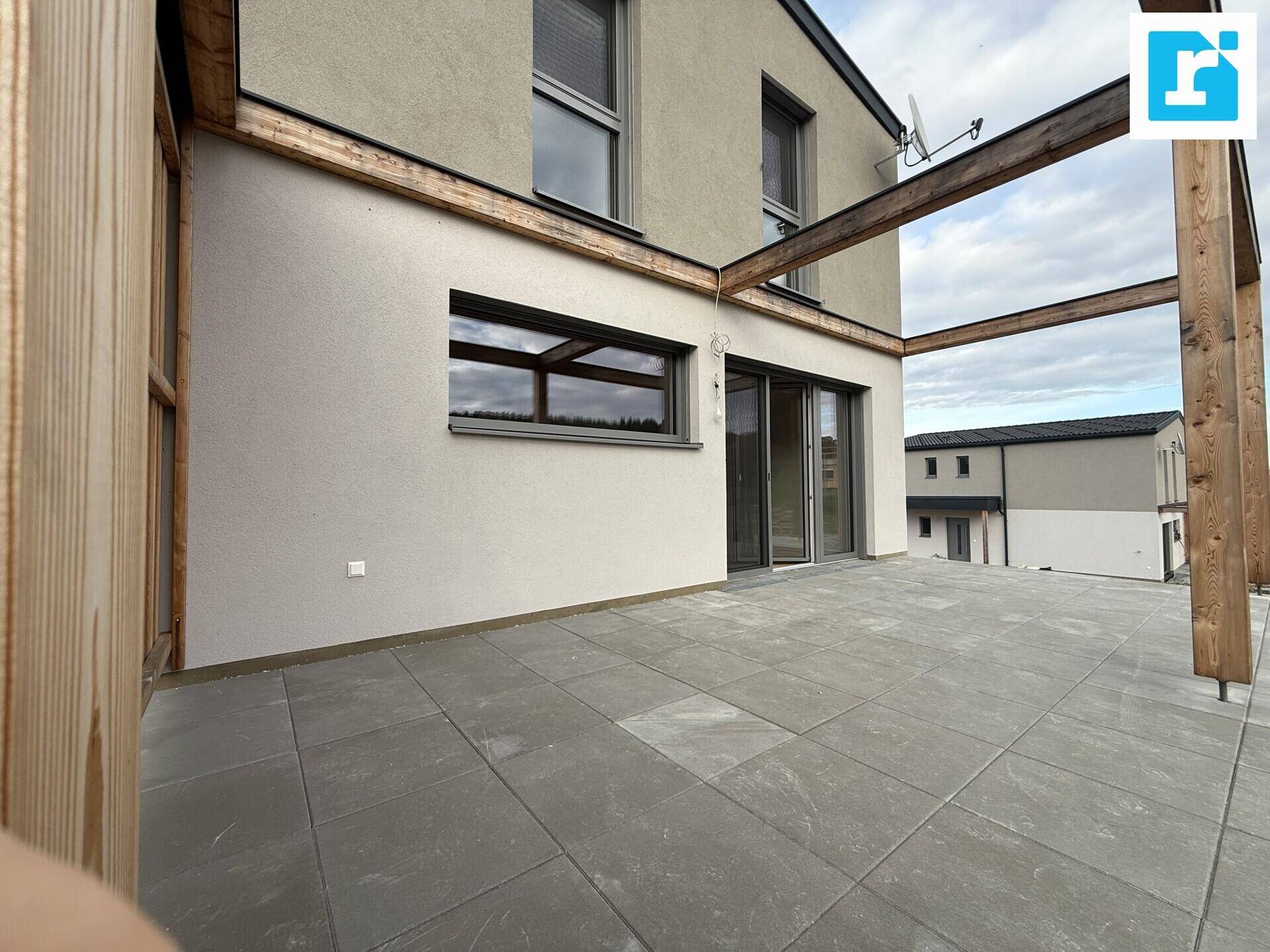 Weitläufige Terrasse mit modernen Fliesen und Blick auf die Umgebung.
